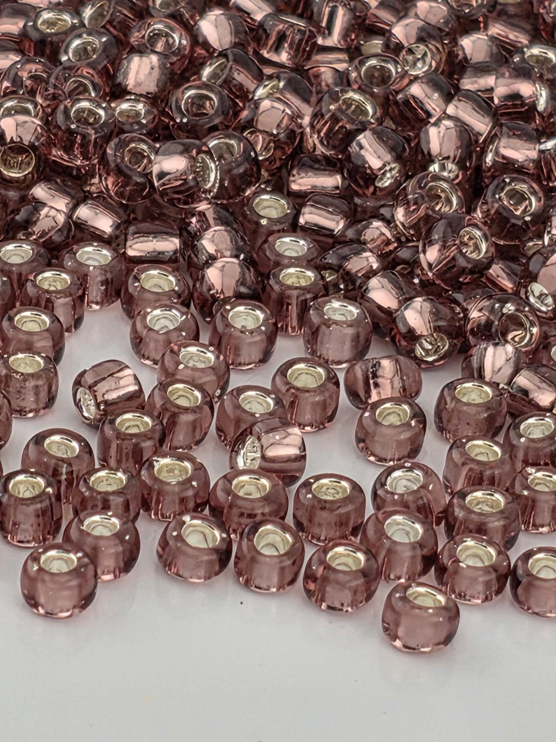 a close-up view of numerous small, clear beads in shades of pink and purple, scattered across a surface.