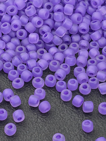 a close-up view of numerous purple beads scattered on a dark surface.