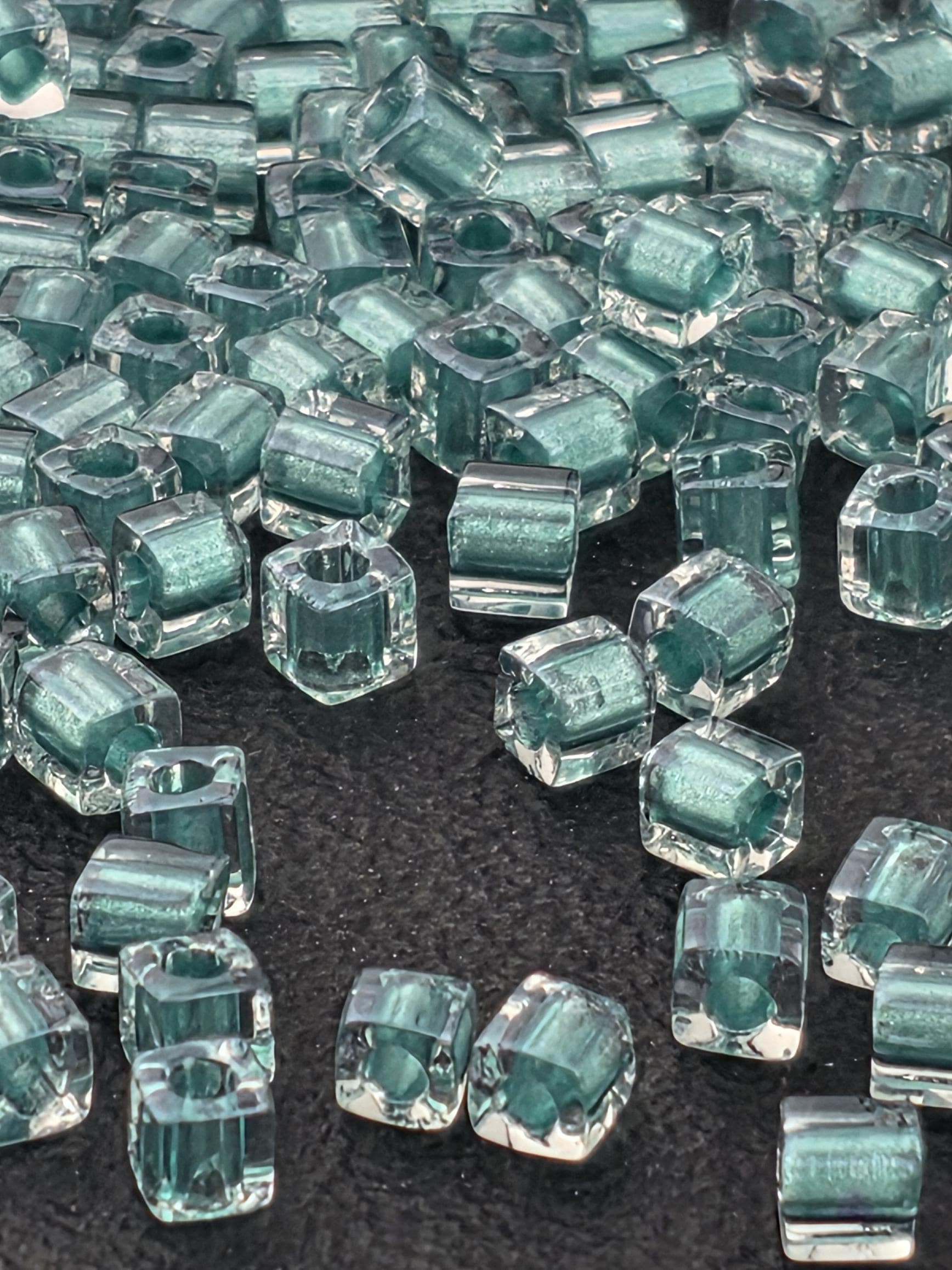 a collection of small, clear glass beads scattered across a dark surface.