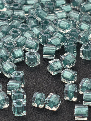 a collection of small, clear glass beads scattered across a dark surface.