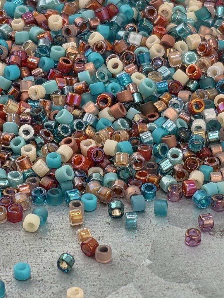A colorful pile of multicolored beads, including various shades of blue, green, orange, and purple, scattered on a surface.