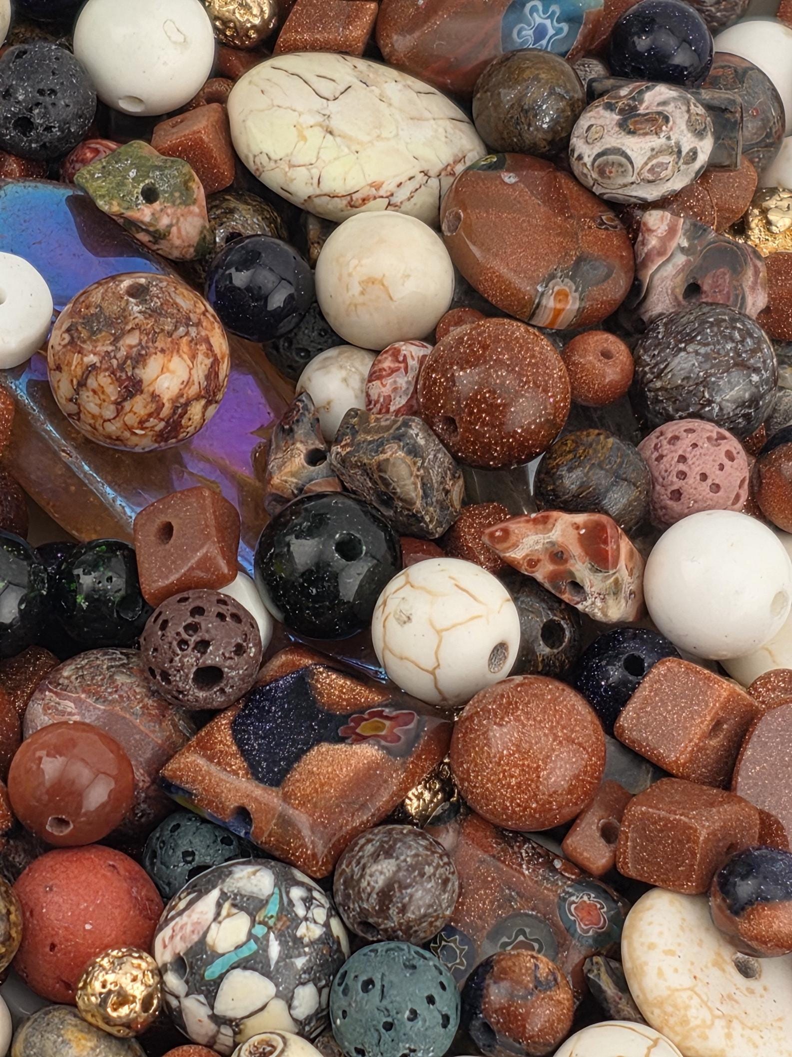 The image is a close-up of a variety of colorful beads and stones, including white, brown, black, and multicolored stones, arranged in a visually appealing manner.
