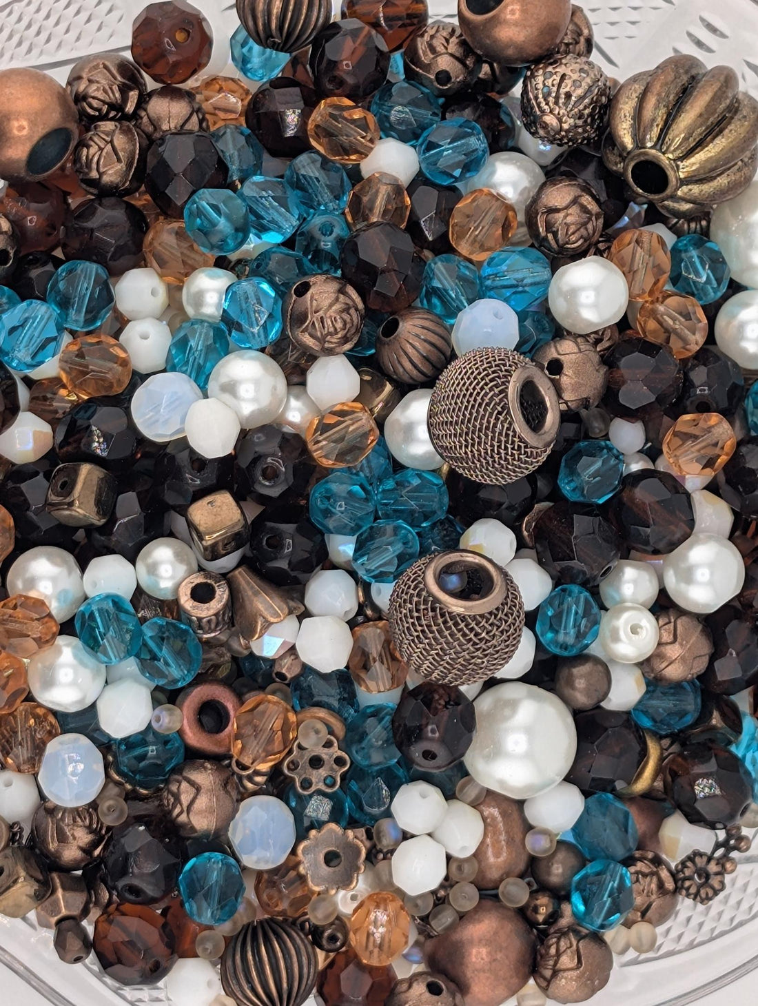 A collection of various beads, including white, blue, and brown, arranged on a white surface.
