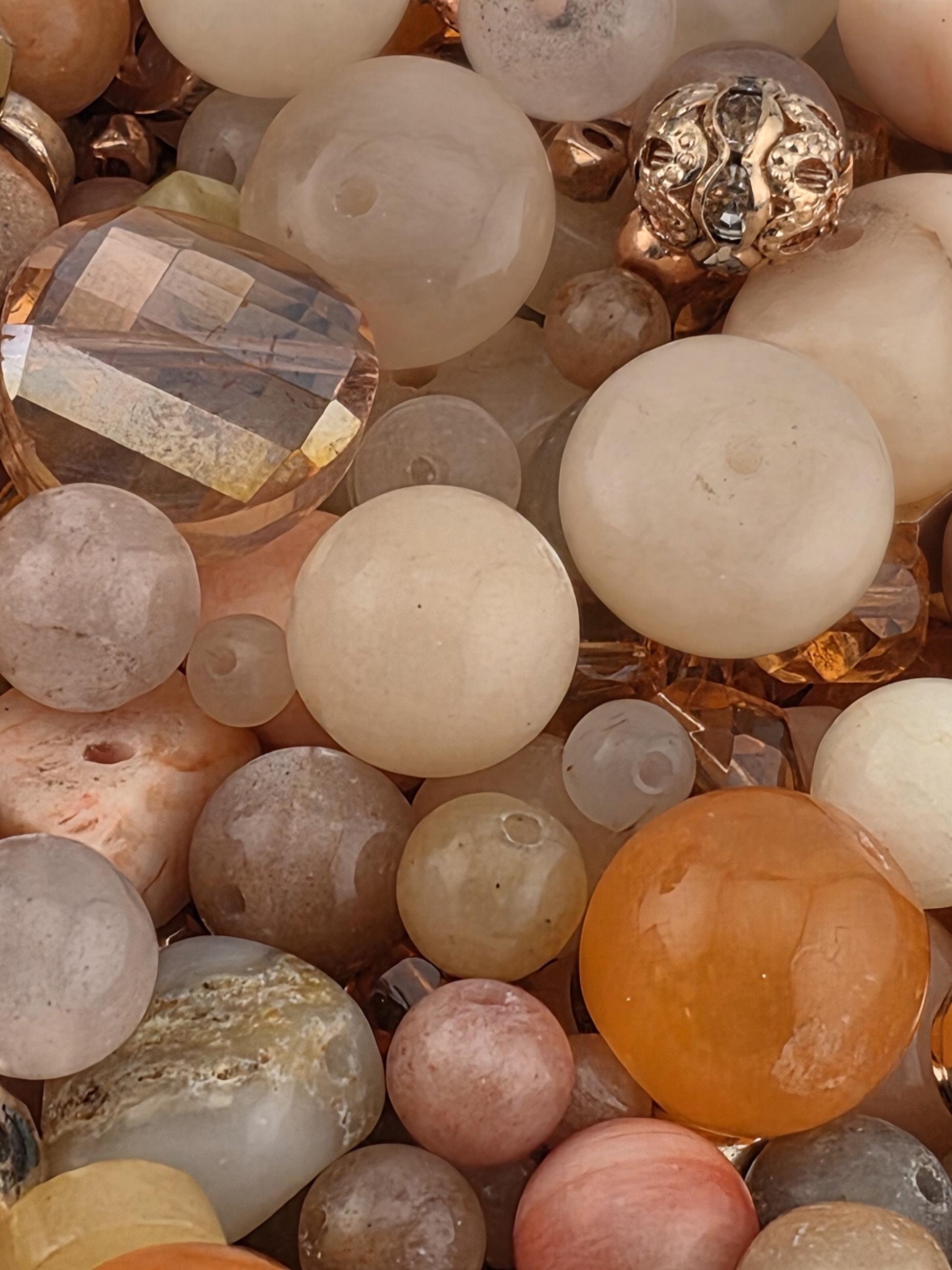 a variety of colorful beads and stones, including white, orange, and pink stones, as well as some clear glass beads.