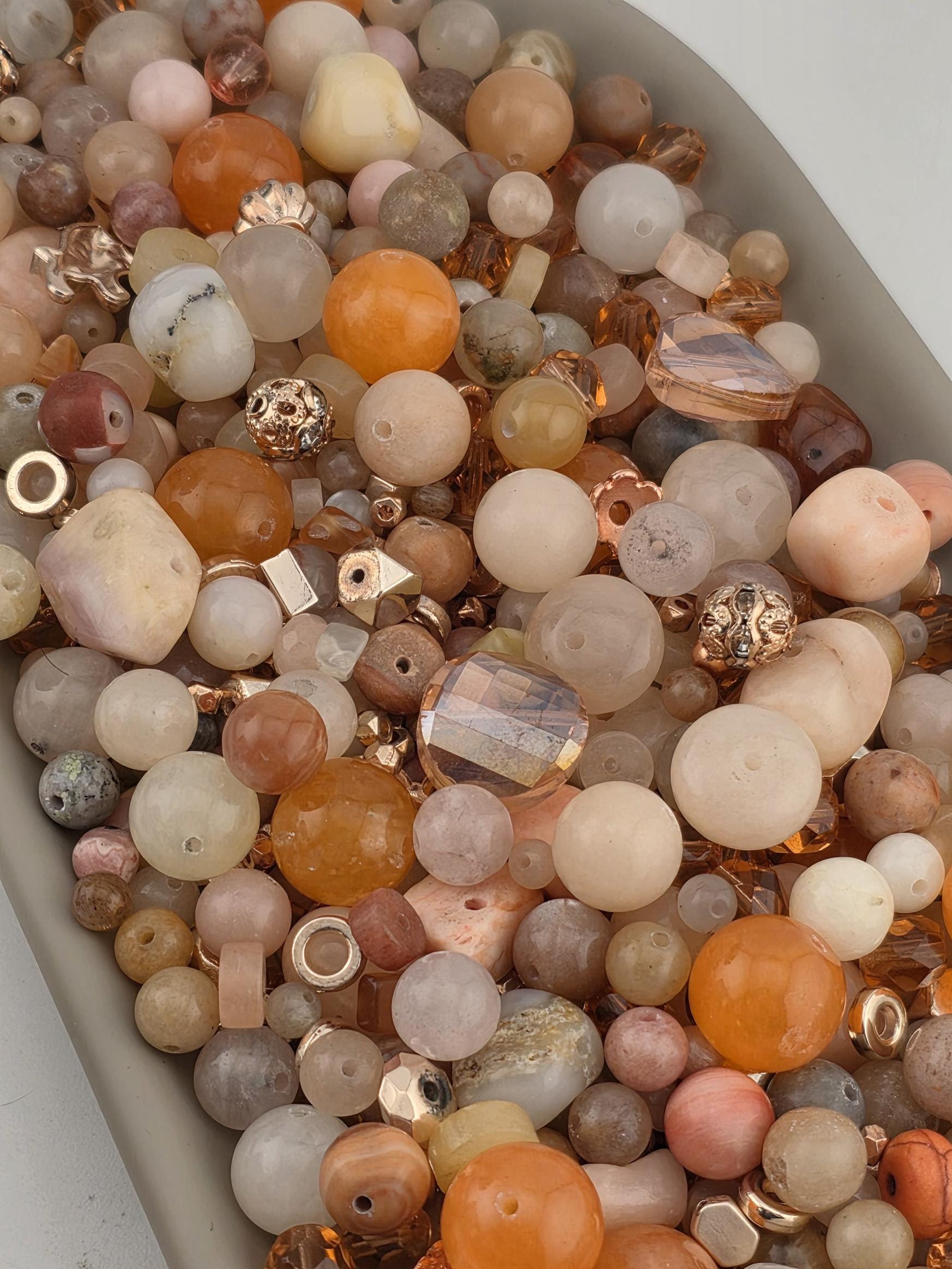 The image is a collection of various beads and beads, including glass, metal, and stone beads, arranged in a visually appealing manner.