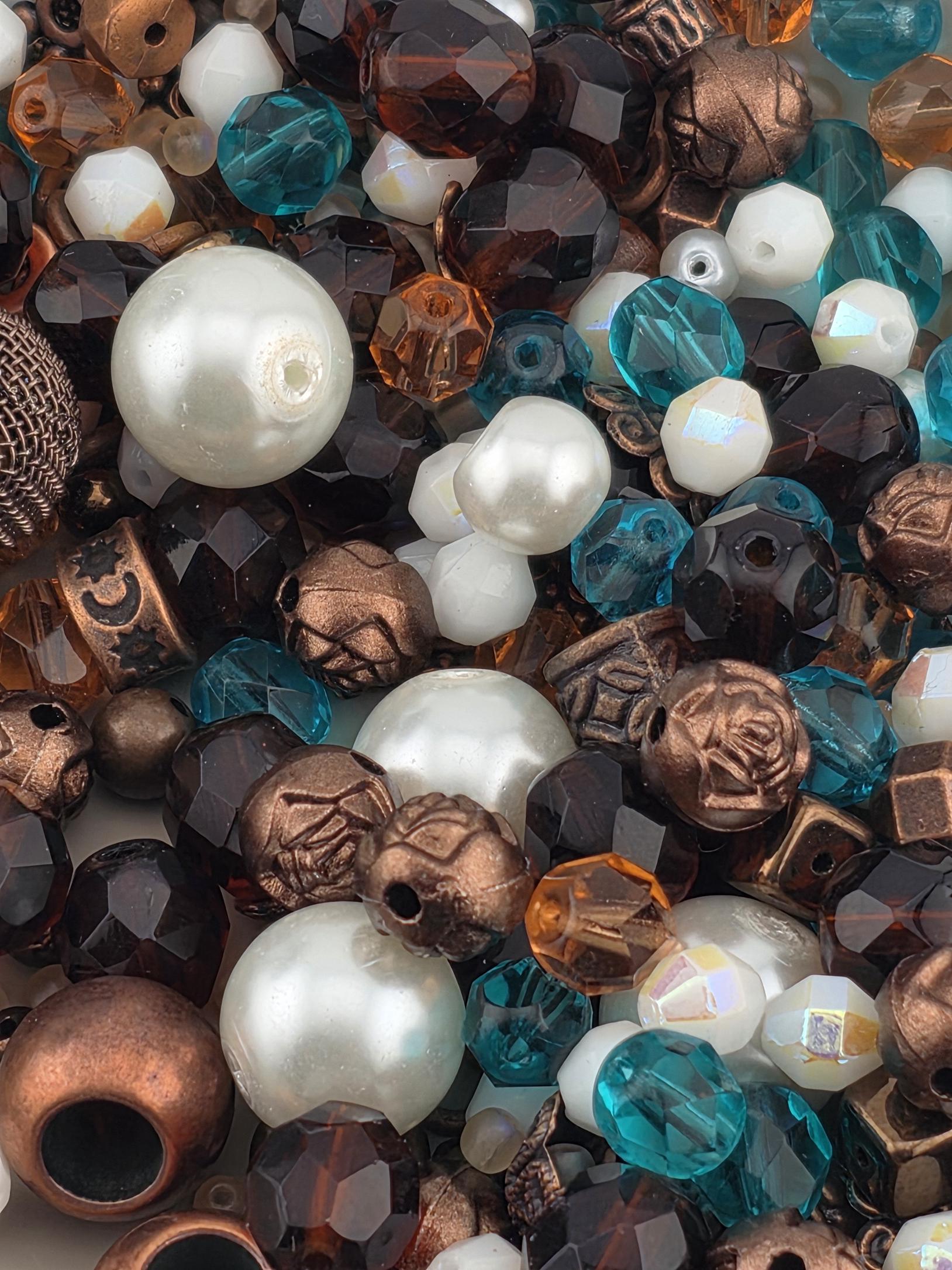 The image is a close-up of various beads and beads, including white, blue, and brown beads, as well as some metallic beads.