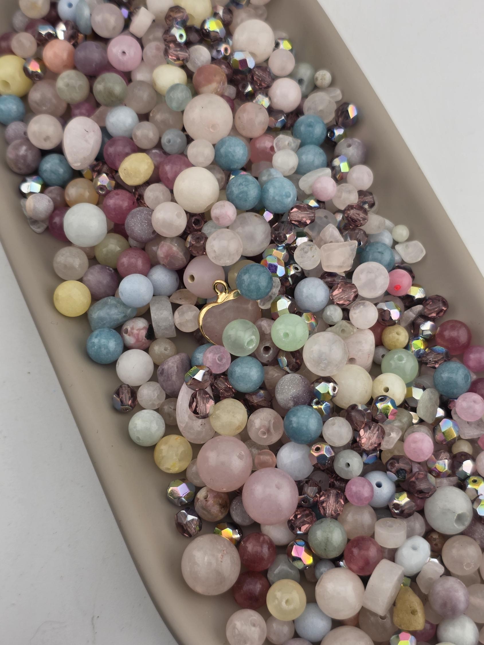 A collection of multicolored beads, including various shades of pink, blue, green, and yellow, arranged on a surface.