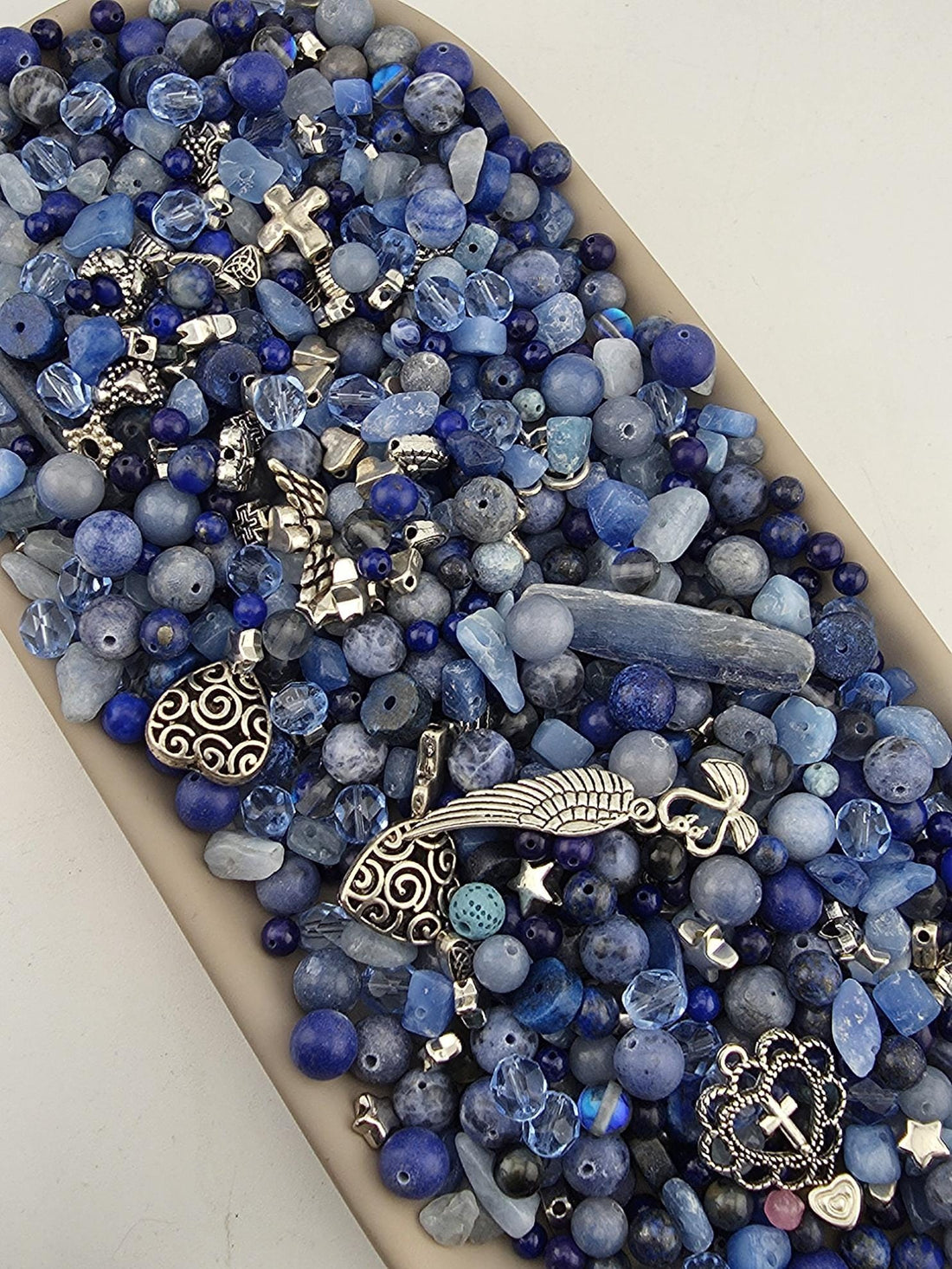 A collection of various blue beads, charms, and other decorative items arranged in a visually appealing manner.