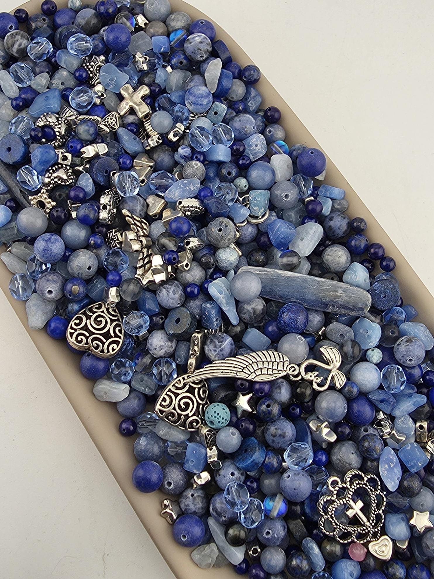 A collection of various blue beads, charms, and other decorative items arranged in a visually appealing manner.