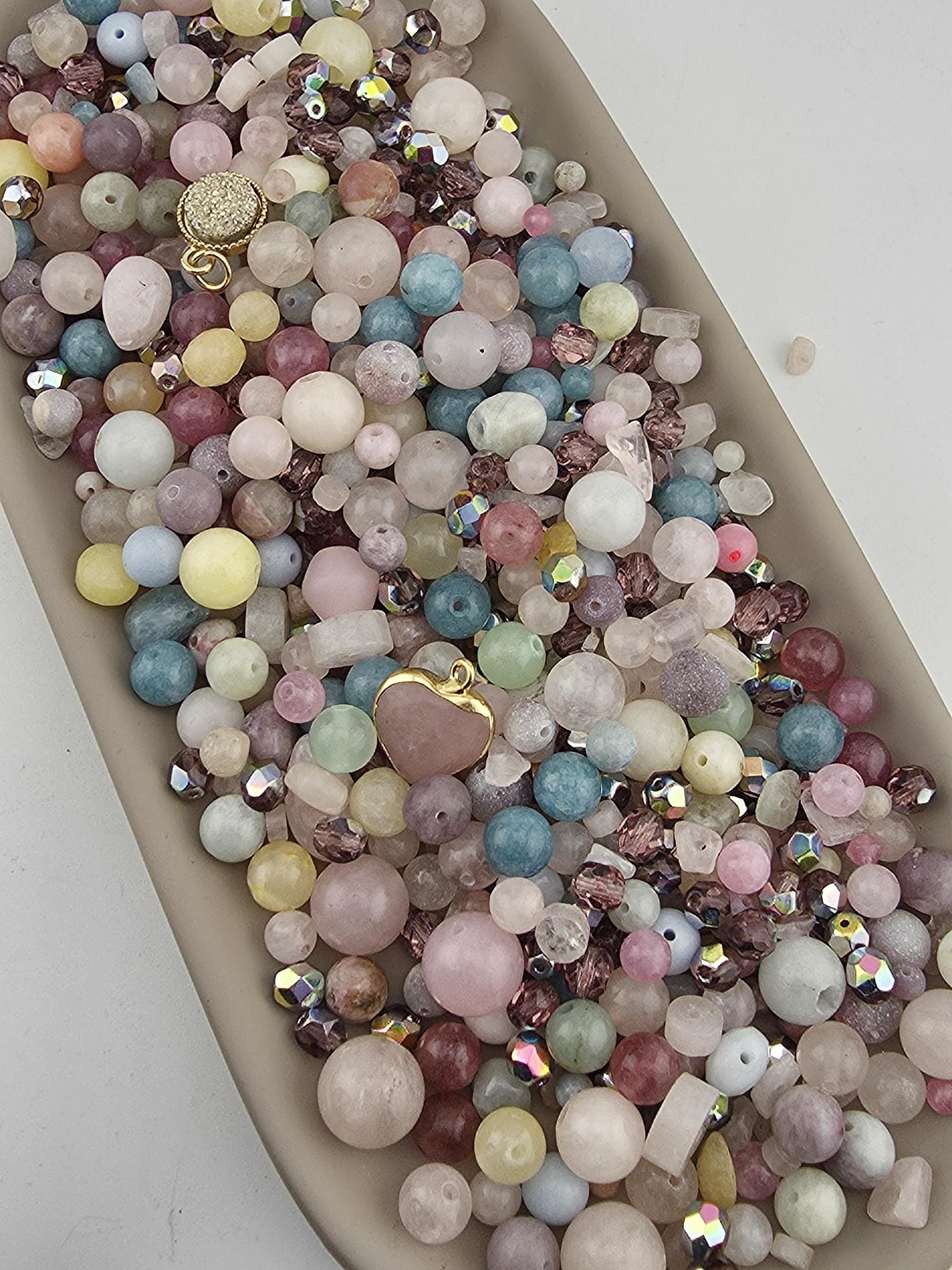 A large collection of colorful beads and gemstones arranged in a tray or container.