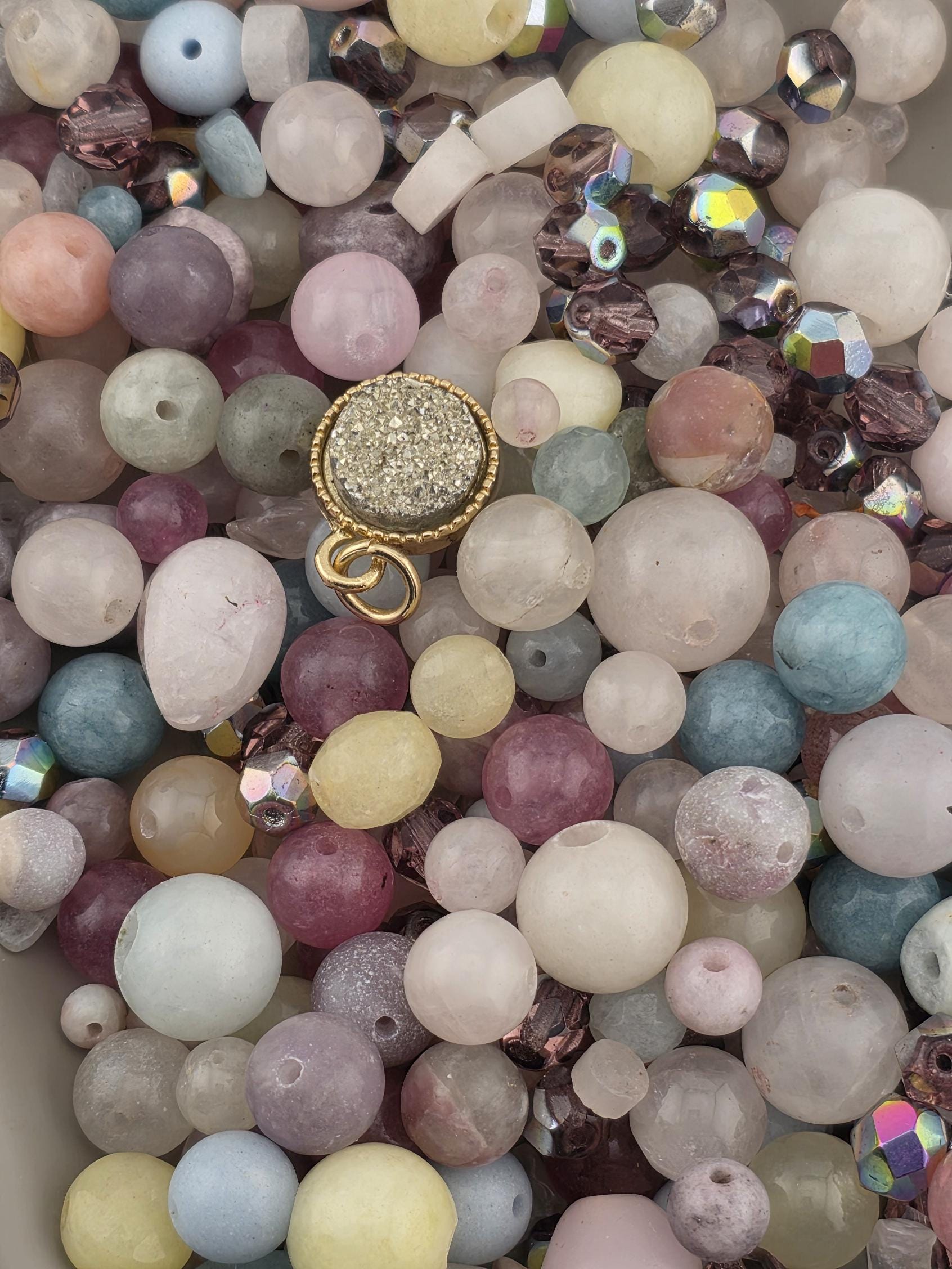 The image is a collage of various colorful beads and gemstones, including clear, pink, blue, and multicolored beads, as well as some gemstones.