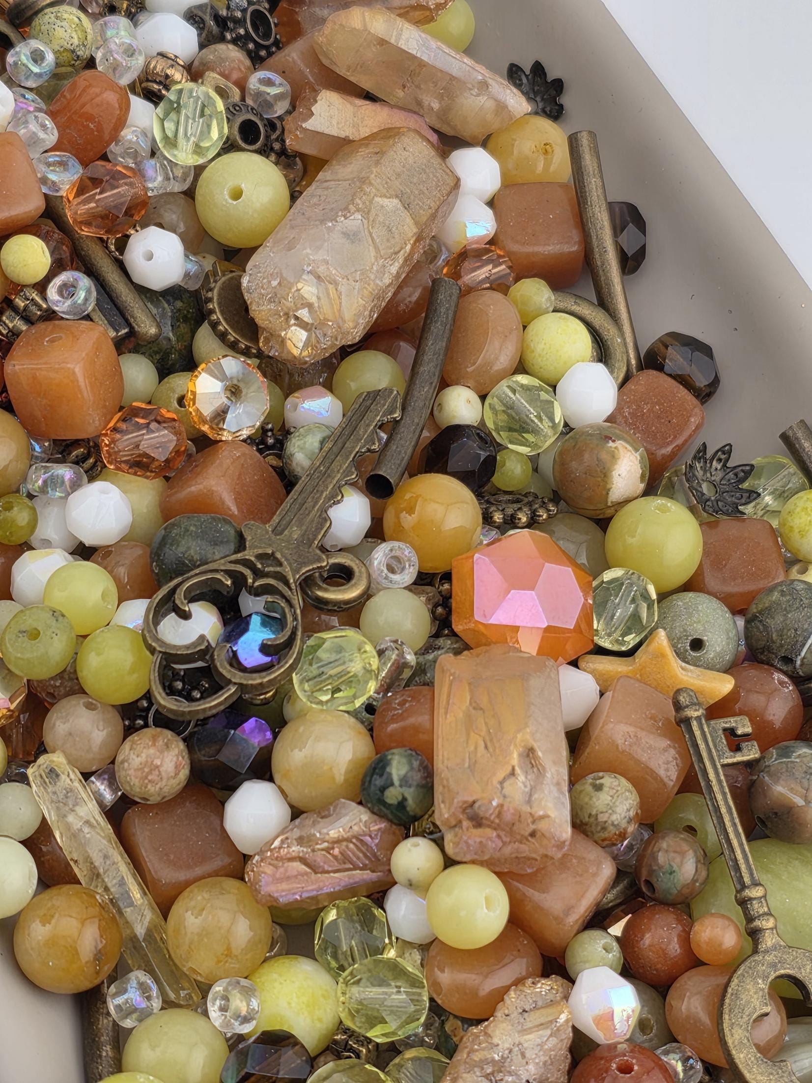 a variety of colorful beads, gemstones, and metal objects, including a key, scattered together.