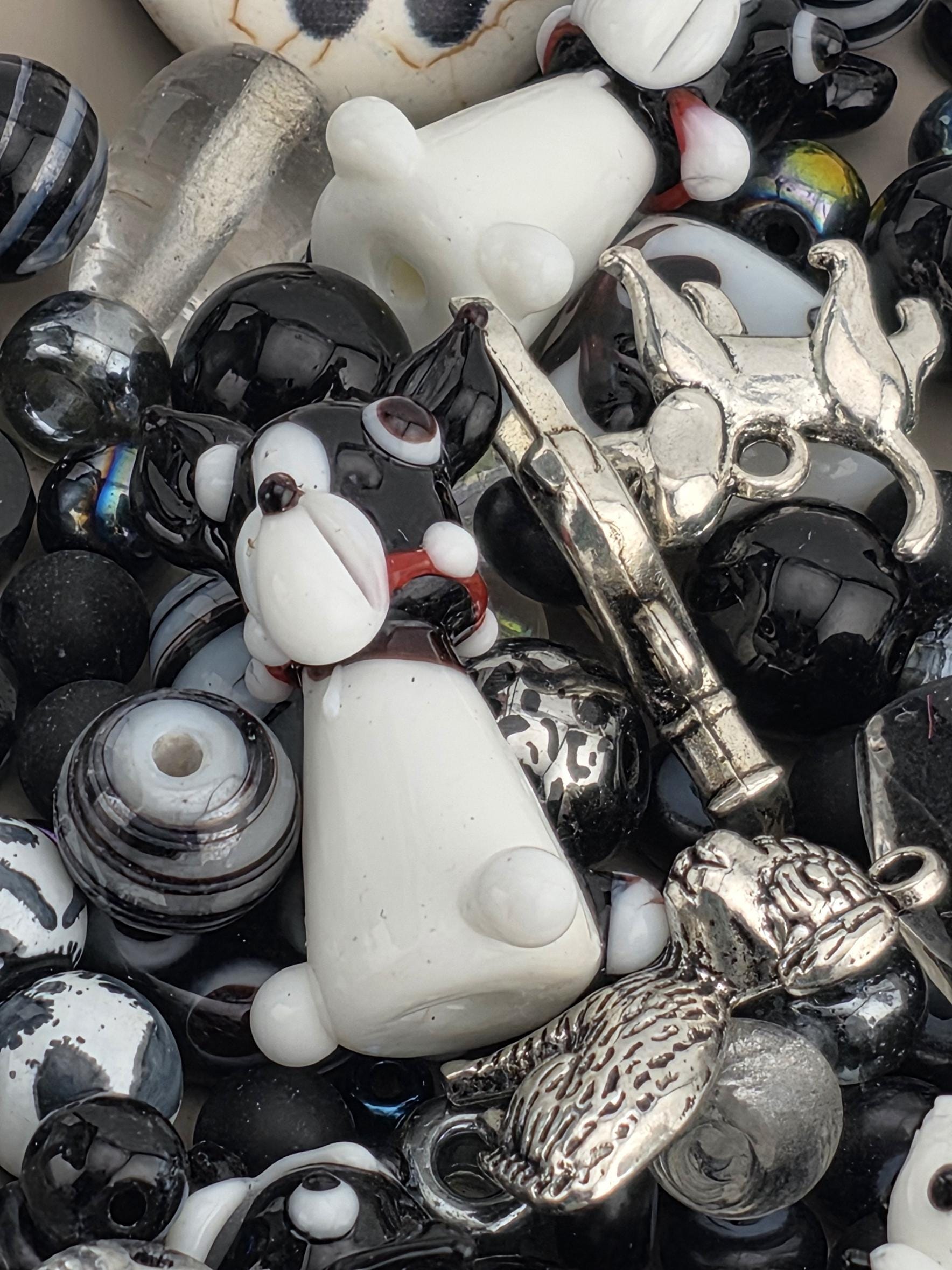 The image is a close-up of various glass beads and metal objects, including a silver-colored metal object and a black and white striped object.