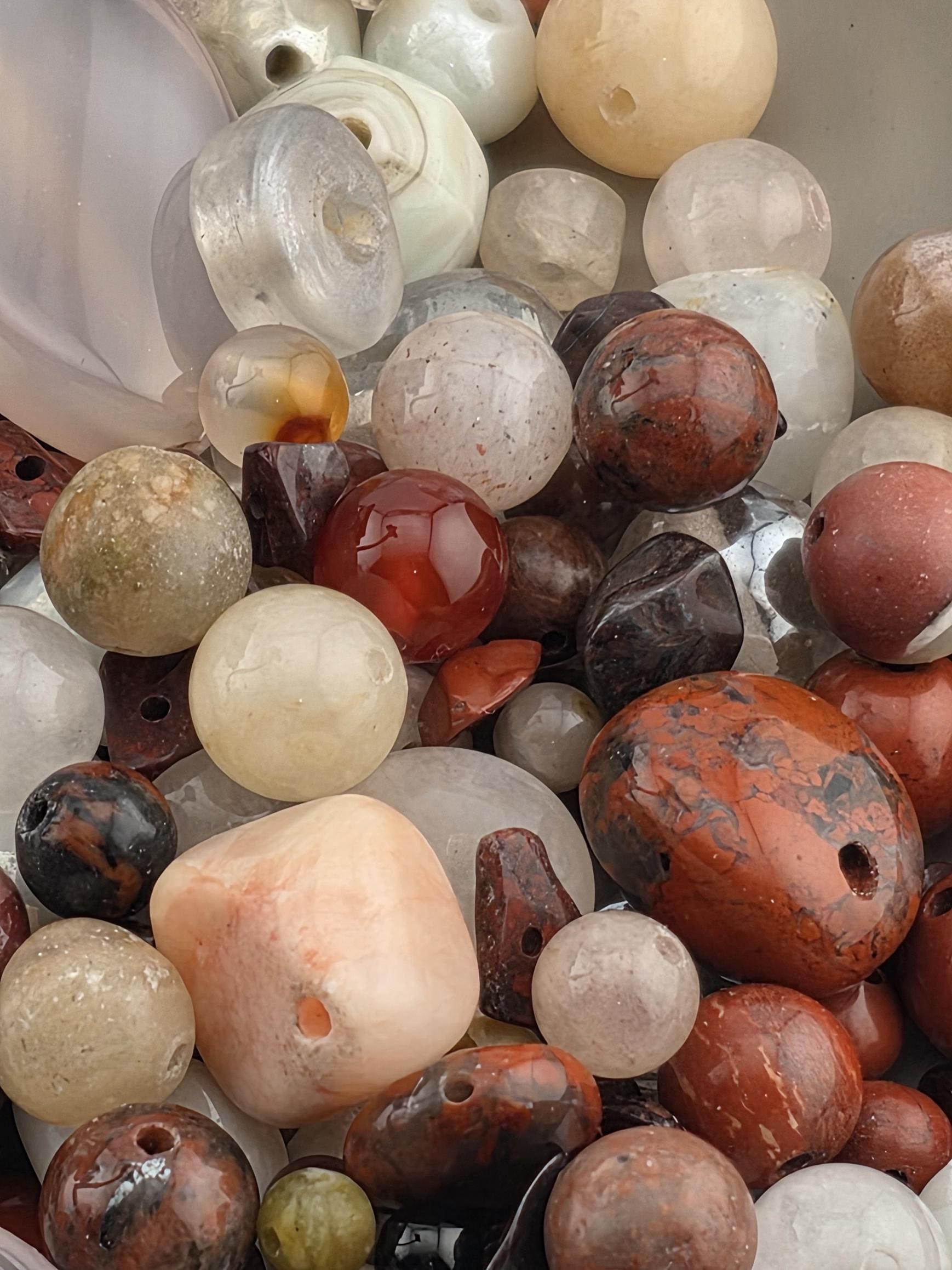 a variety of colorful beads and stones, including clear, red, and white beads, as well as other natural elements like rocks and shells.