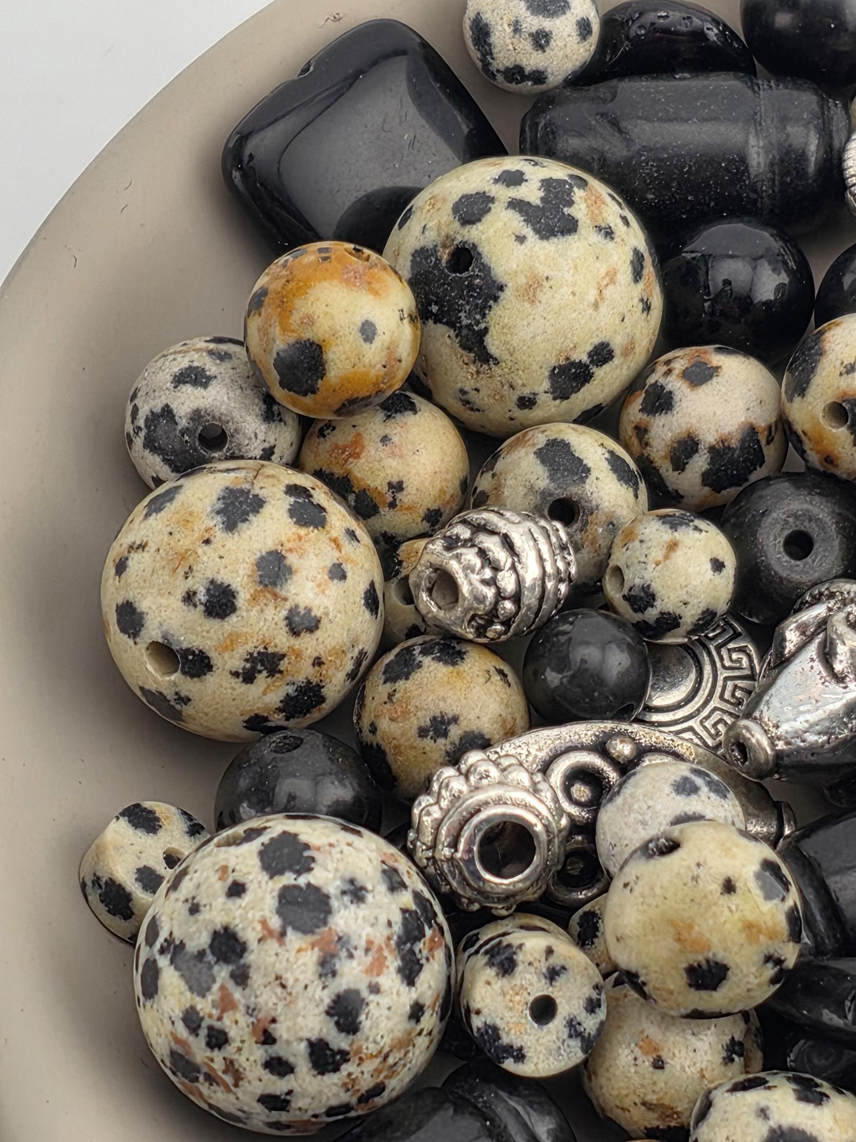 a collection of various beads and beads with a speckled pattern, including black and white beads, as well as some with a speckled pattern and a silver-colored bead.