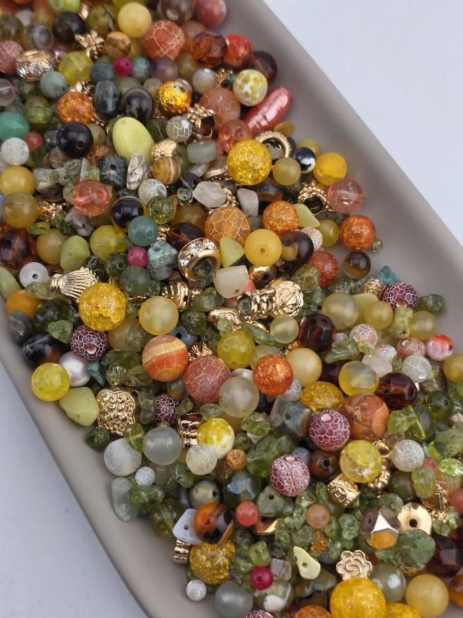 a large pile of various colorful beads, including glass, metal, and plastic beads, scattered on a surface.