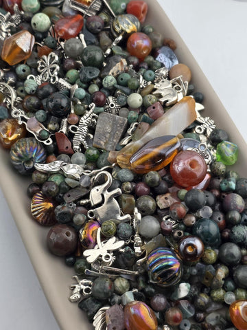 A collection of various beads, charms, and other decorative items arranged in a container.