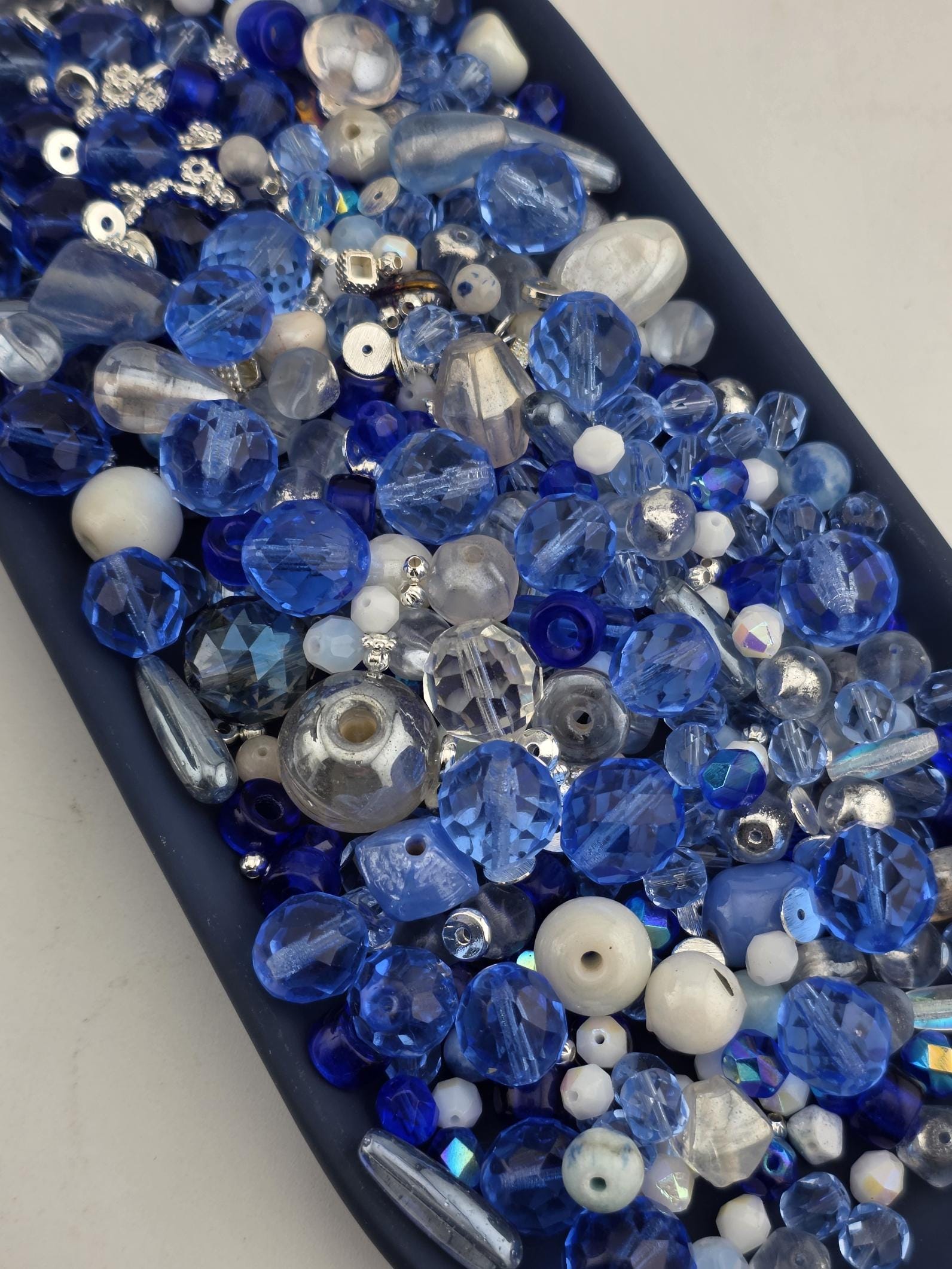 A collection of various blue and silver beads, including clear, blue, and silver beads, arranged in a visually appealing manner.