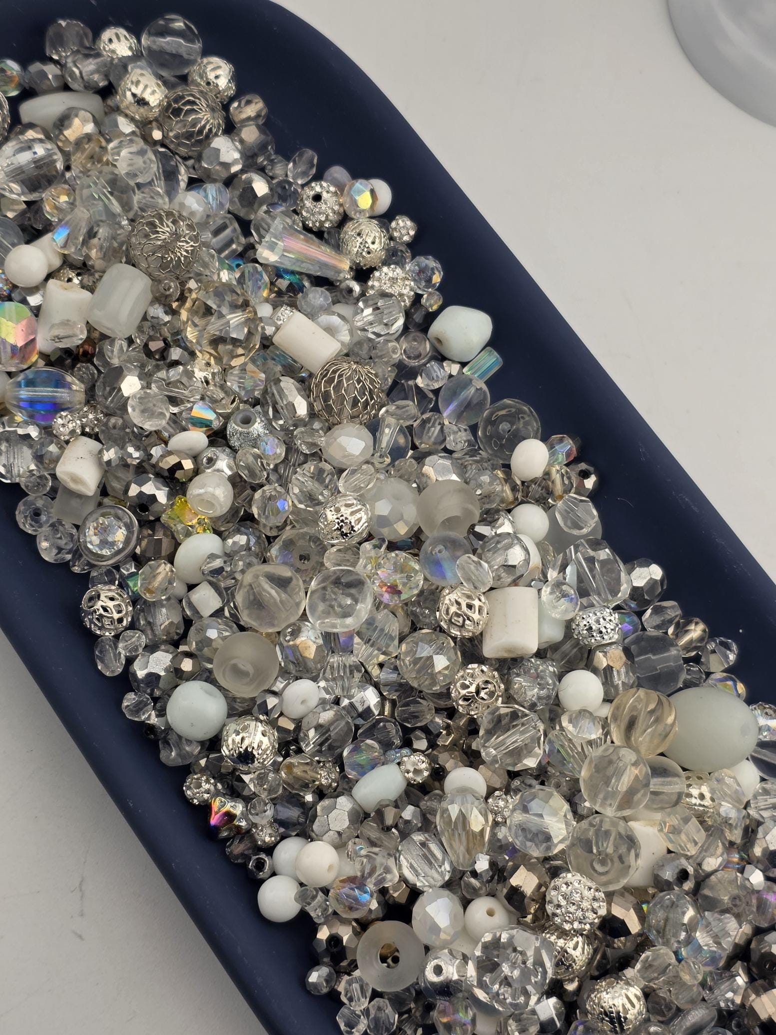A collection of various clear beads and crystals arranged on a dark surface.