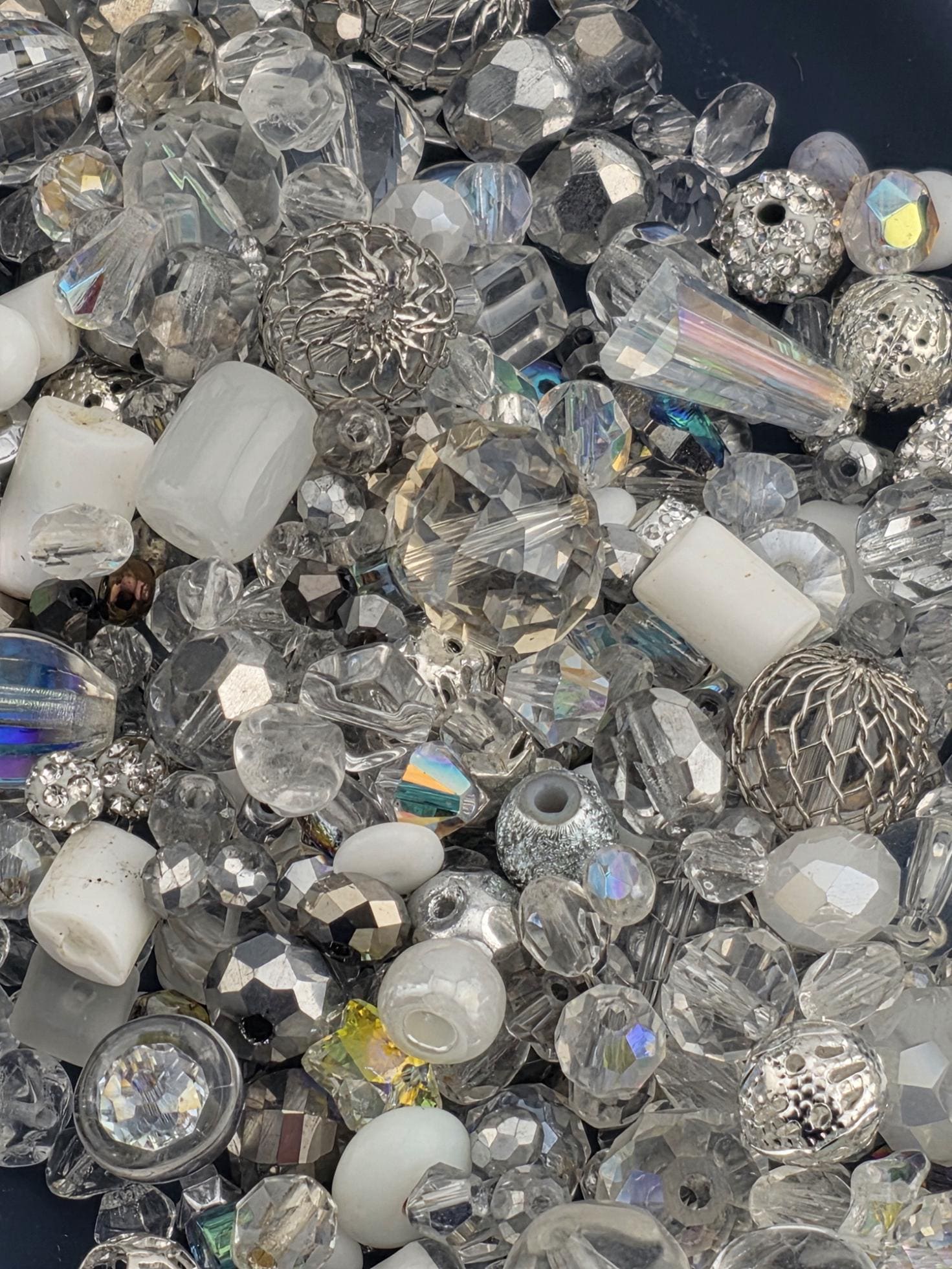 The image is a close-up of various glass beads and crystals, showcasing their intricate and diverse shapes and sizes.
