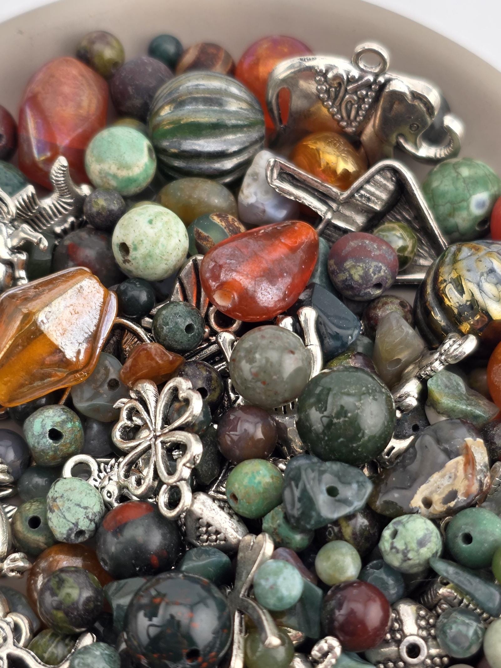 A close-up image of a collection of colorful beads, charms, and metal objects, including beads, charms, and metal pieces, arranged together.