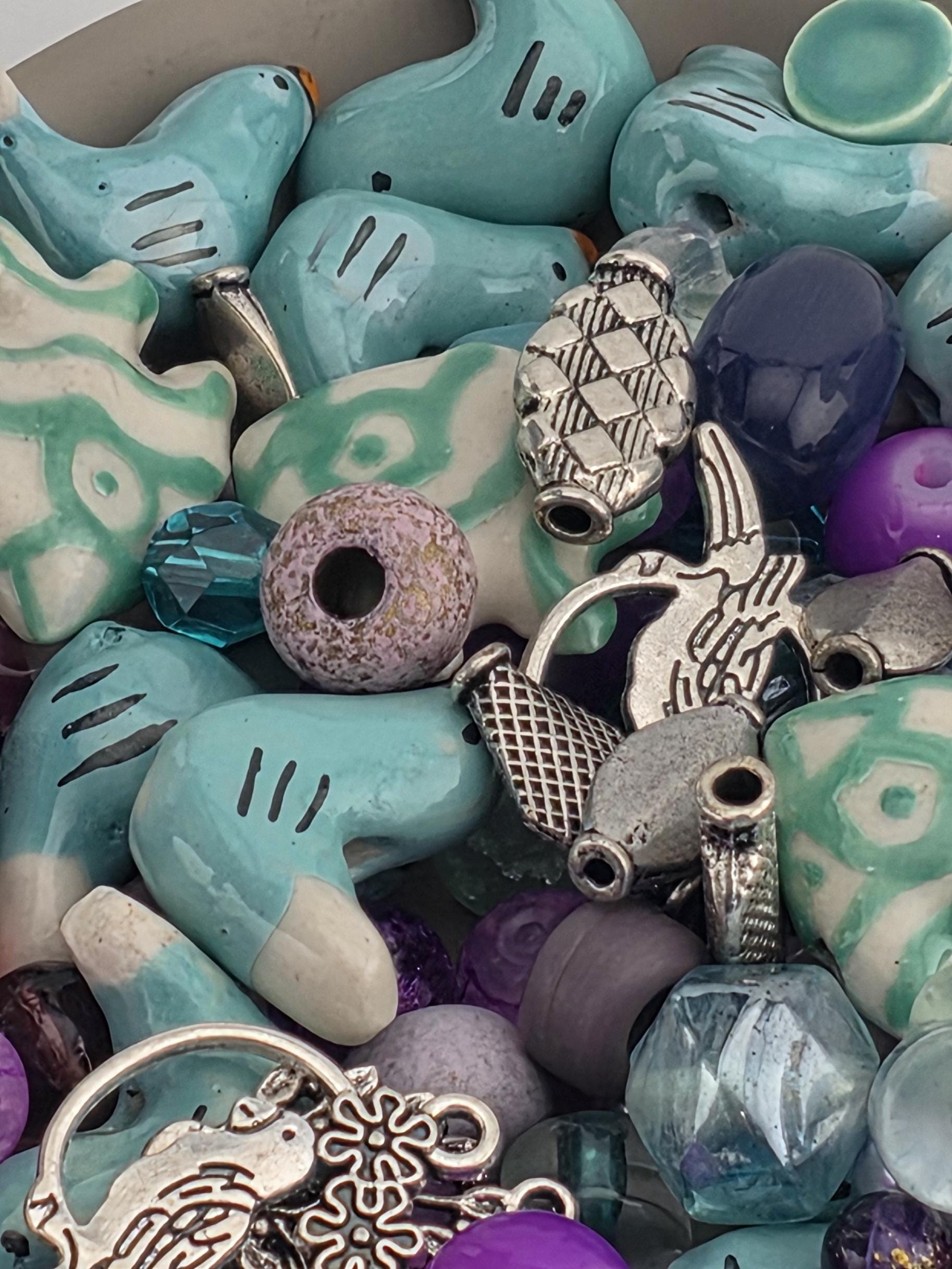 The image is a close-up of various colorful beads and charms, including blue, purple, and silver elements, arranged in a visually appealing manner.
