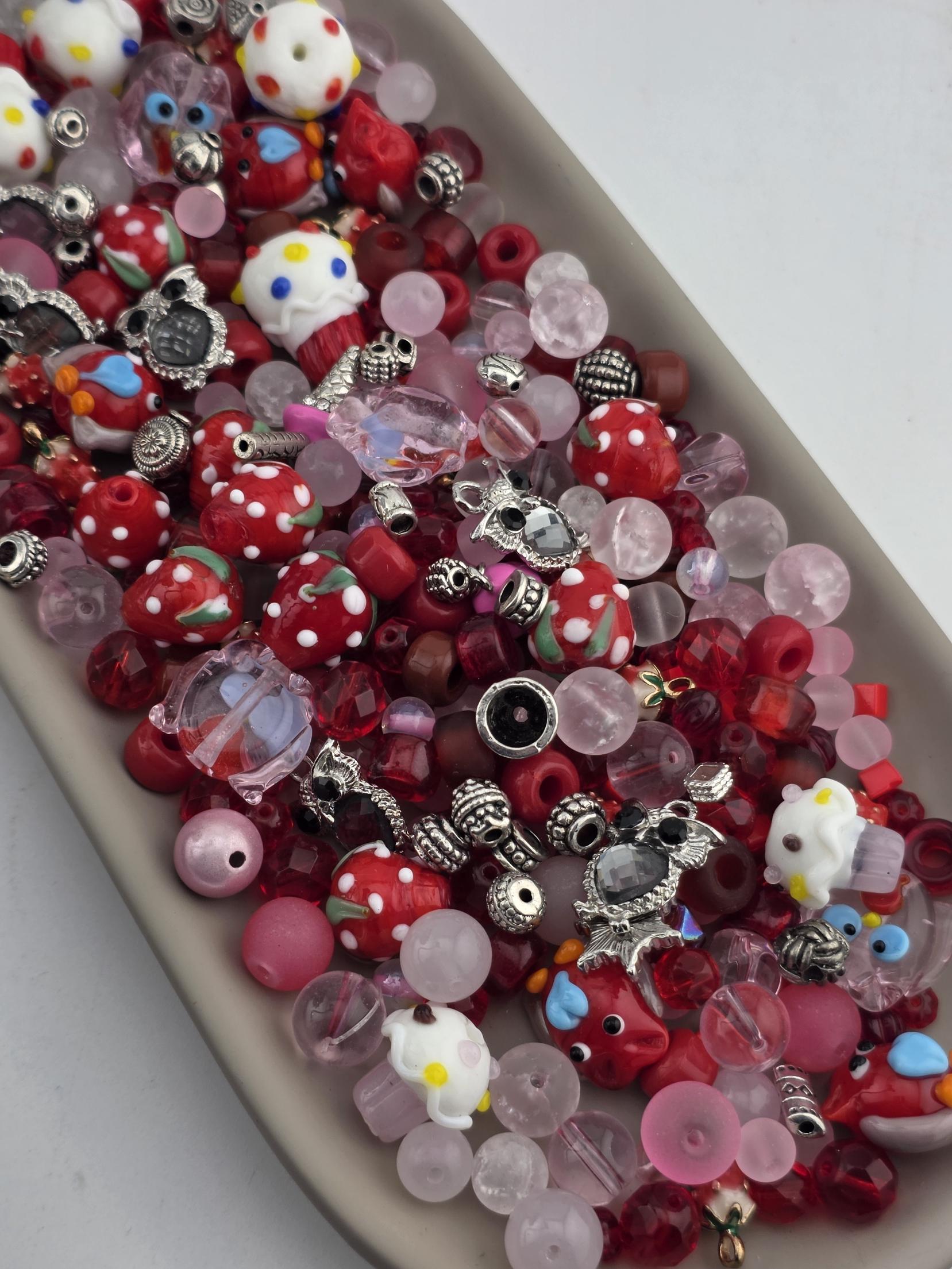 A tray filled with various colorful beads, charms, and other decorative items.