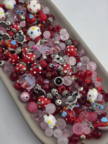 A tray filled with various colorful beads, charms, and other decorative items.