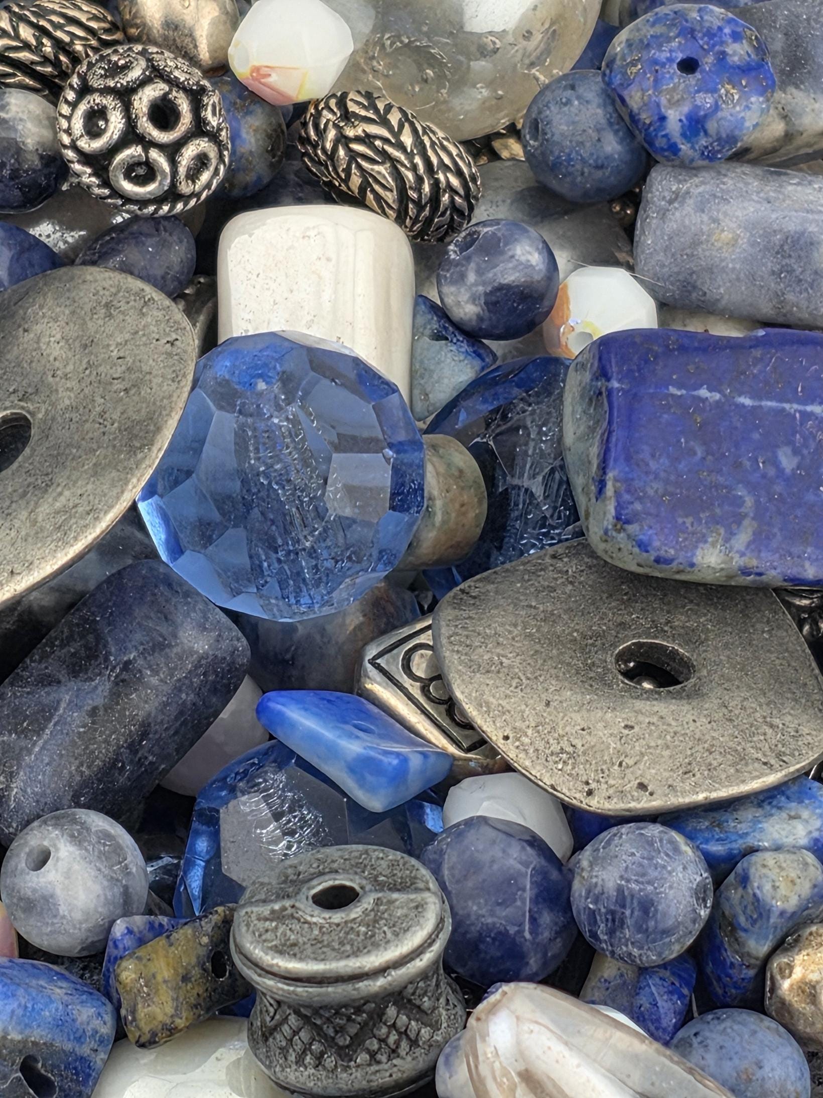 a variety of blue and silver beads, including clear and silver beads, as well as some metal beads, all scattered together.