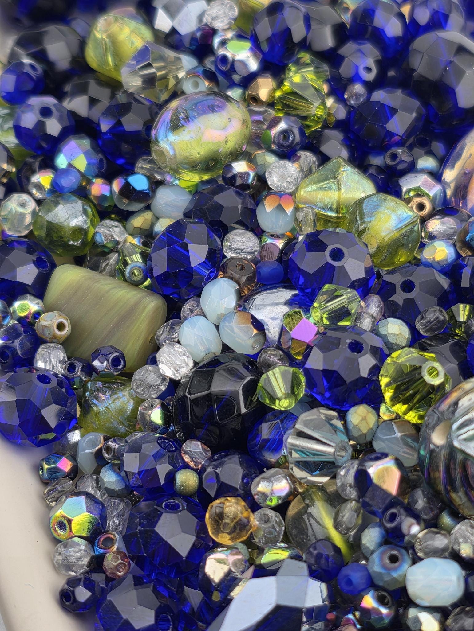 A close-up image of a collection of colorful glass beads, including blue, green, yellow, and silver beads, arranged in a visually appealing manner.