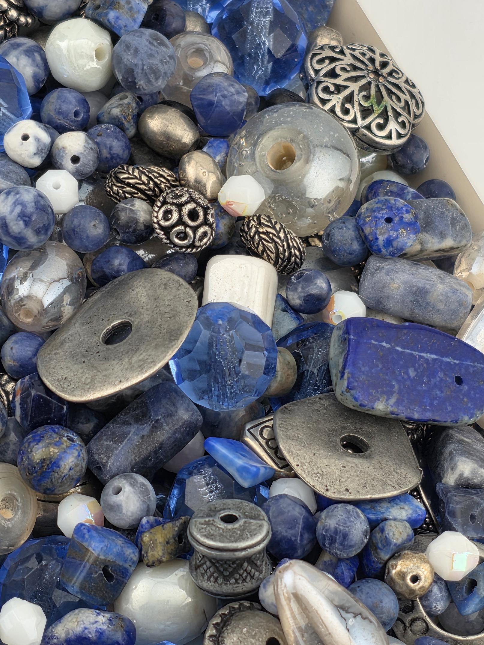 a variety of blue and silver beads, including clear and blue beads, as well as some metal beads, arranged in a visually appealing manner.