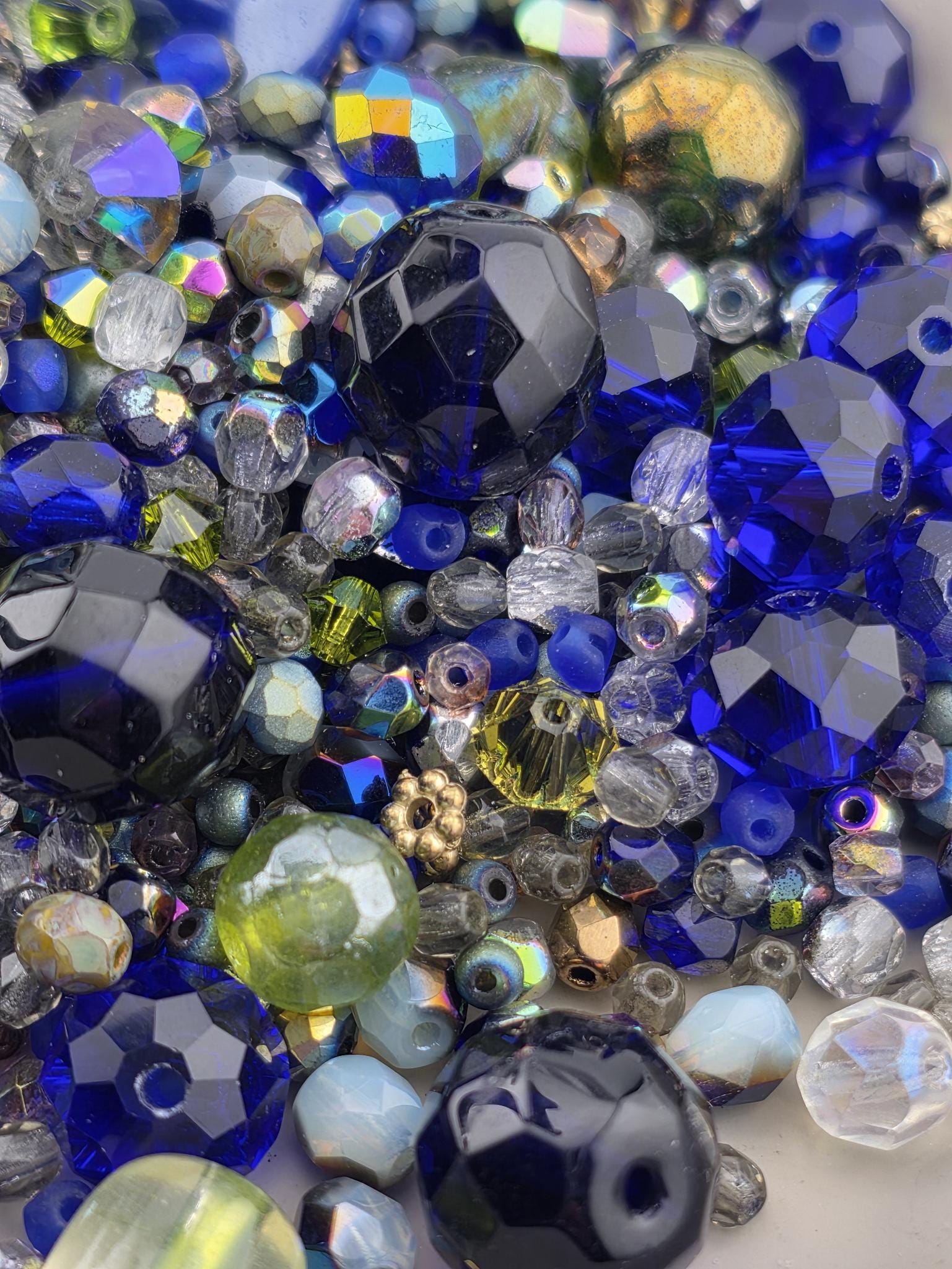 A close-up image of a collection of colorful glass beads, including blue, green, yellow, and silver beads, arranged in a visually appealing manner.
