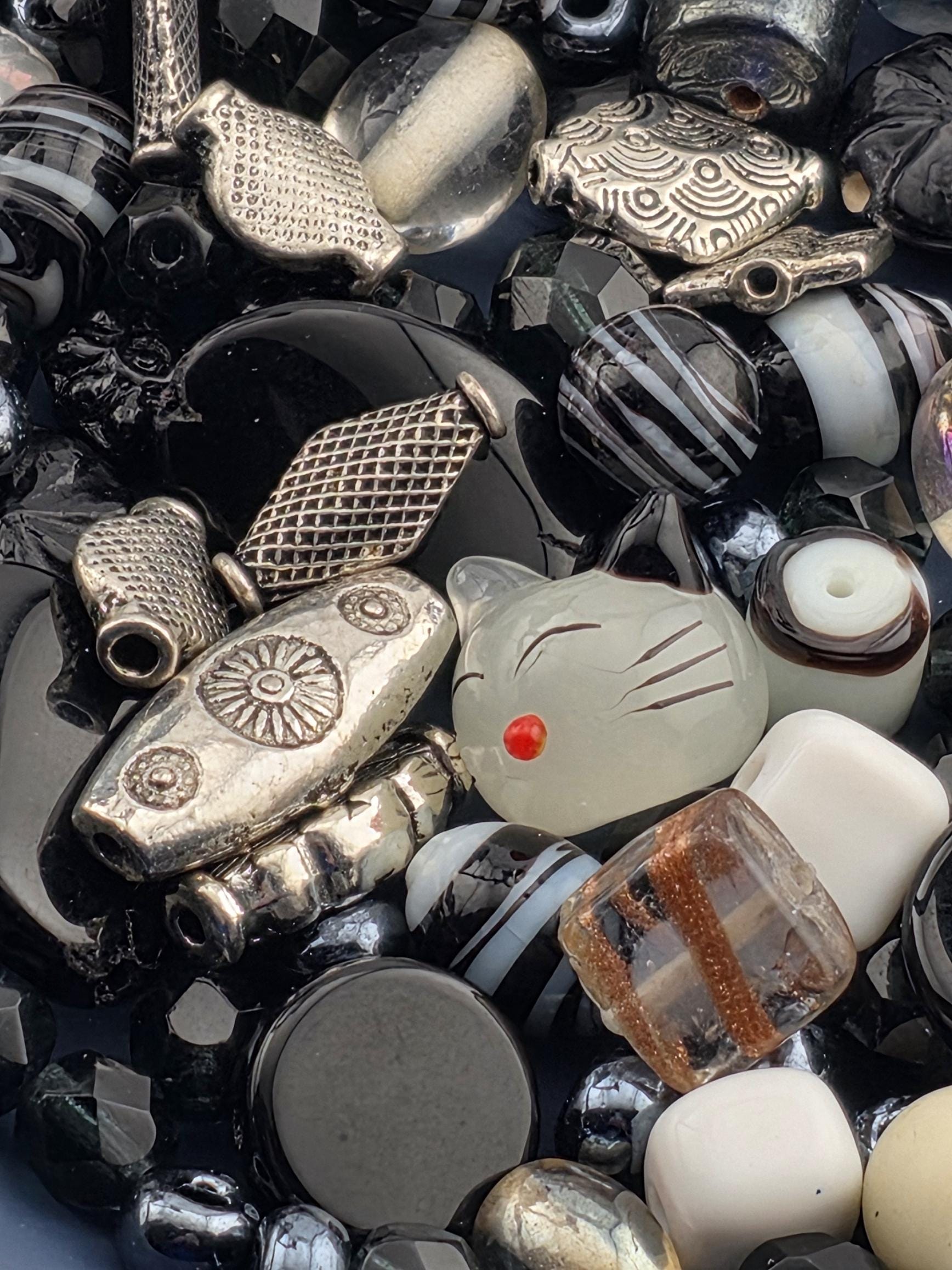 a variety of beads and metal pieces, including glass beads, metal beads, and other decorative elements, arranged in a visually appealing manner.