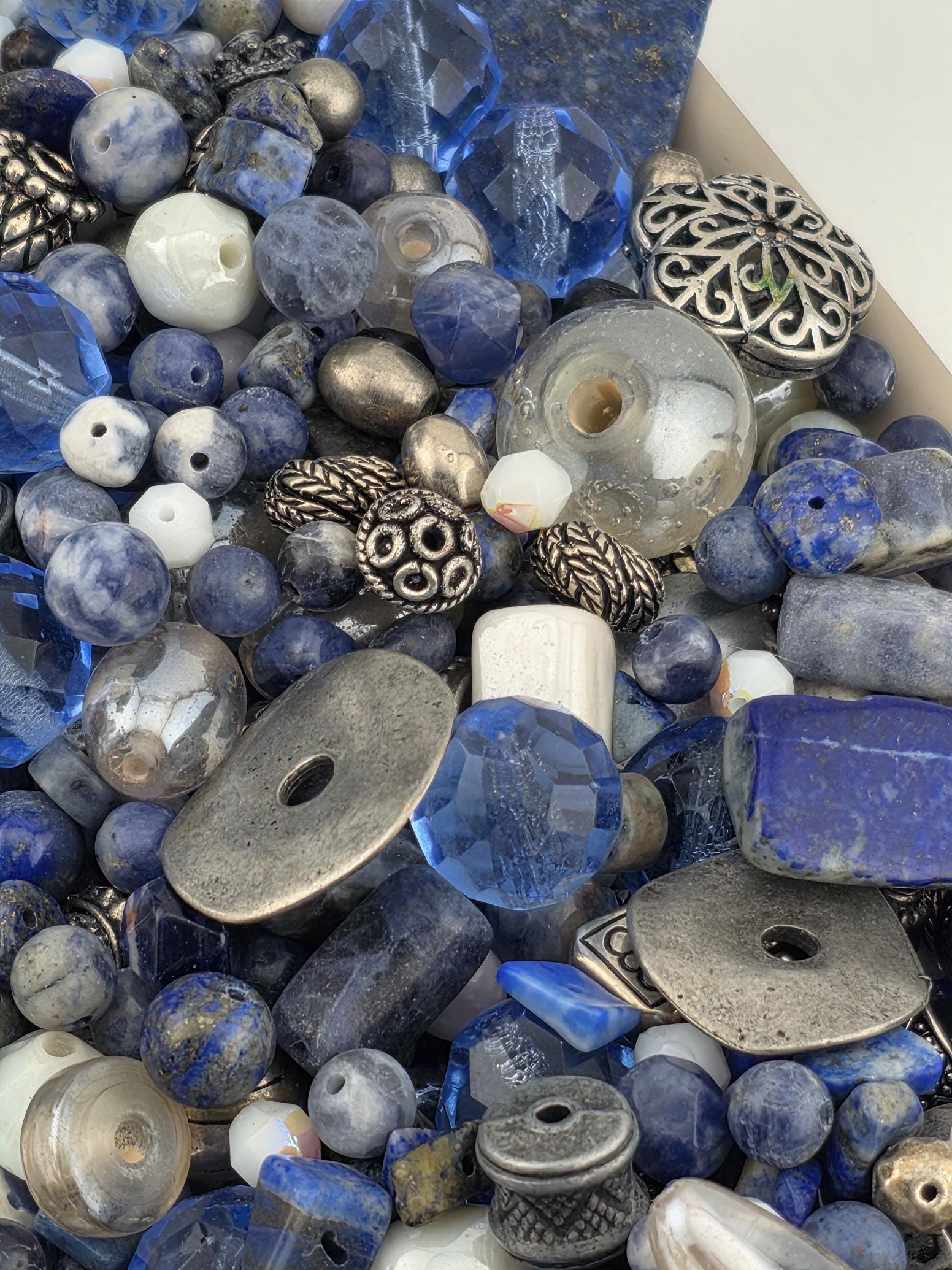a variety of blue and silver beads, charms, and other decorative objects, creating a visually appealing and diverse collection.
