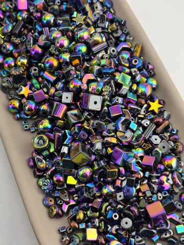The image is a close-up of a collection of multicolored glass beads, including various shapes and sizes, scattered on a surface.