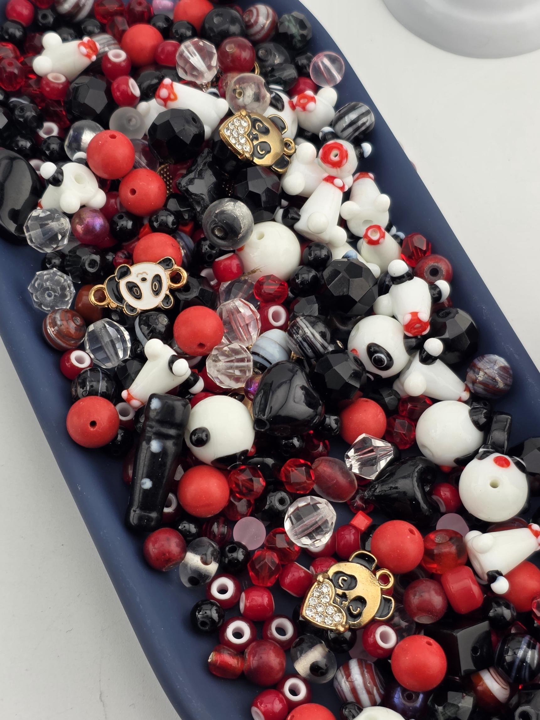 A blue tray filled with various beads, charms, and other decorative items in shades of red, black, and white.