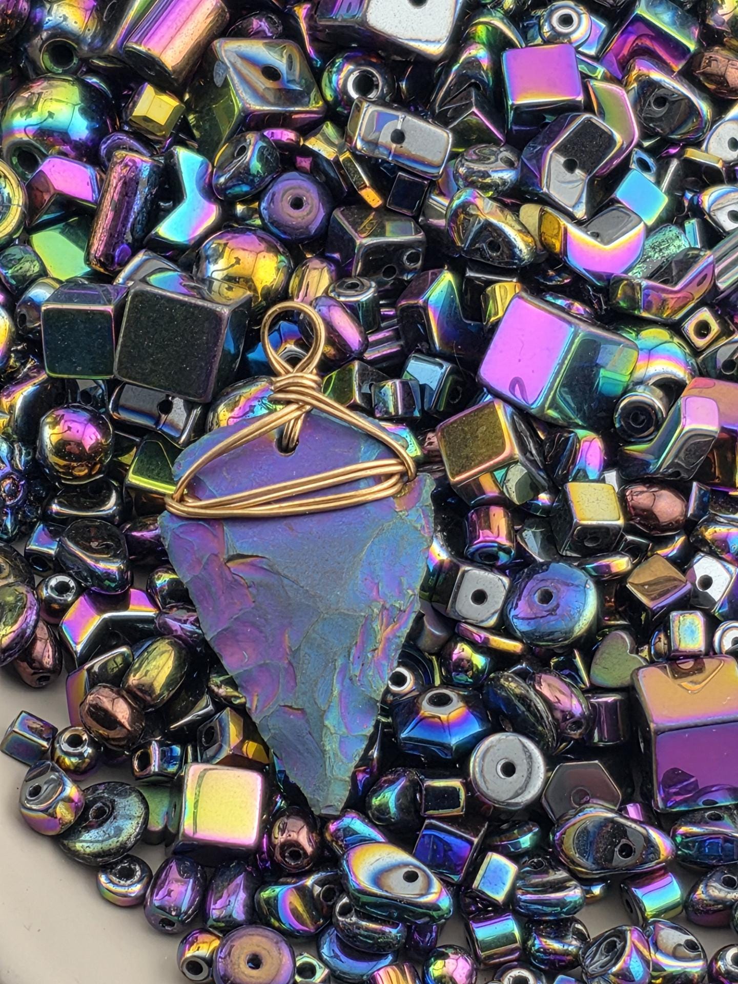 The image is a close-up of a collection of colorful glass beads and stones, including various shapes and sizes, arranged in a visually appealing manner.