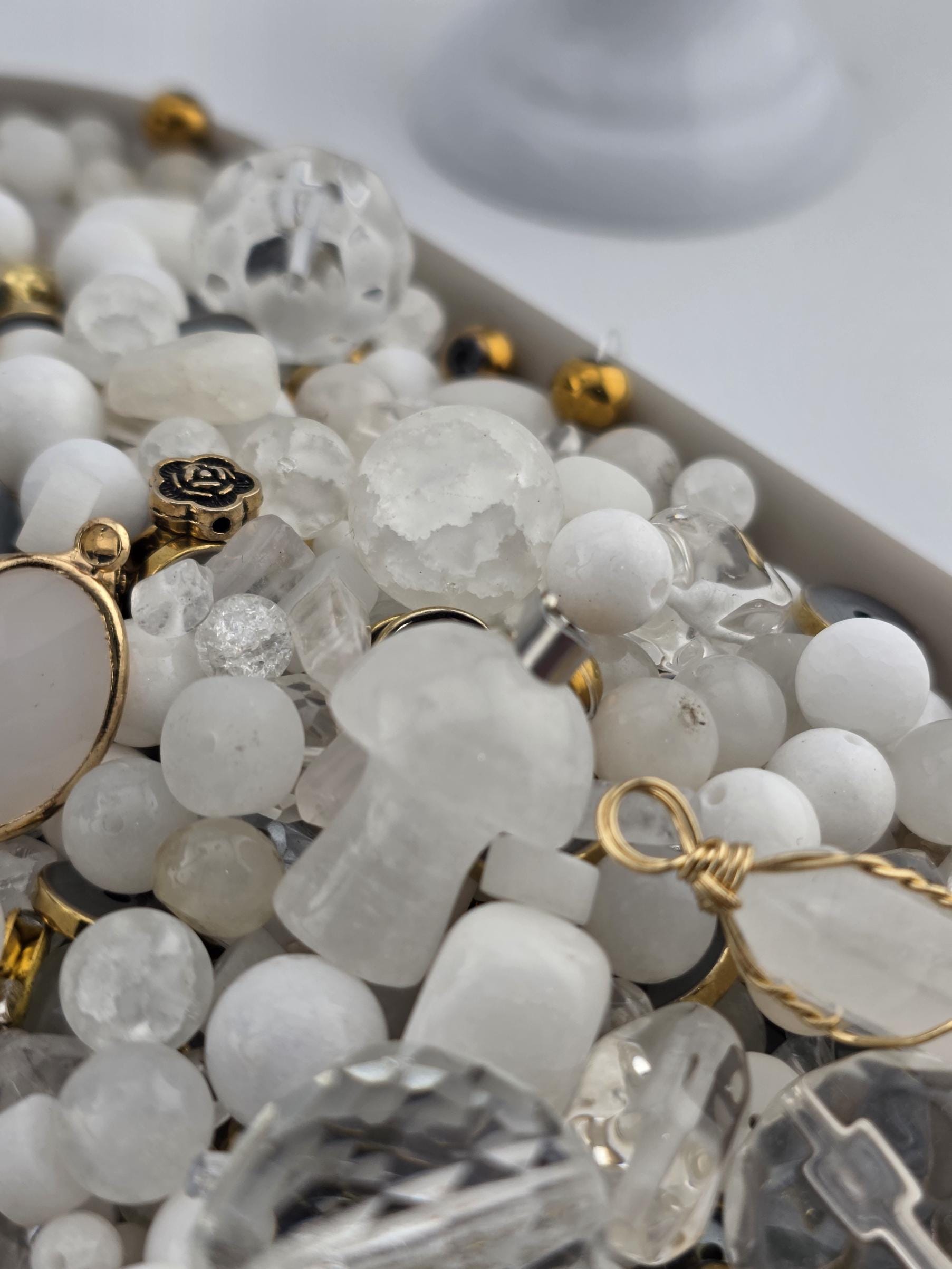 The image is a close-up of various crystal beads and jewelry pieces, including clear beads, gemstones, and metal components.
