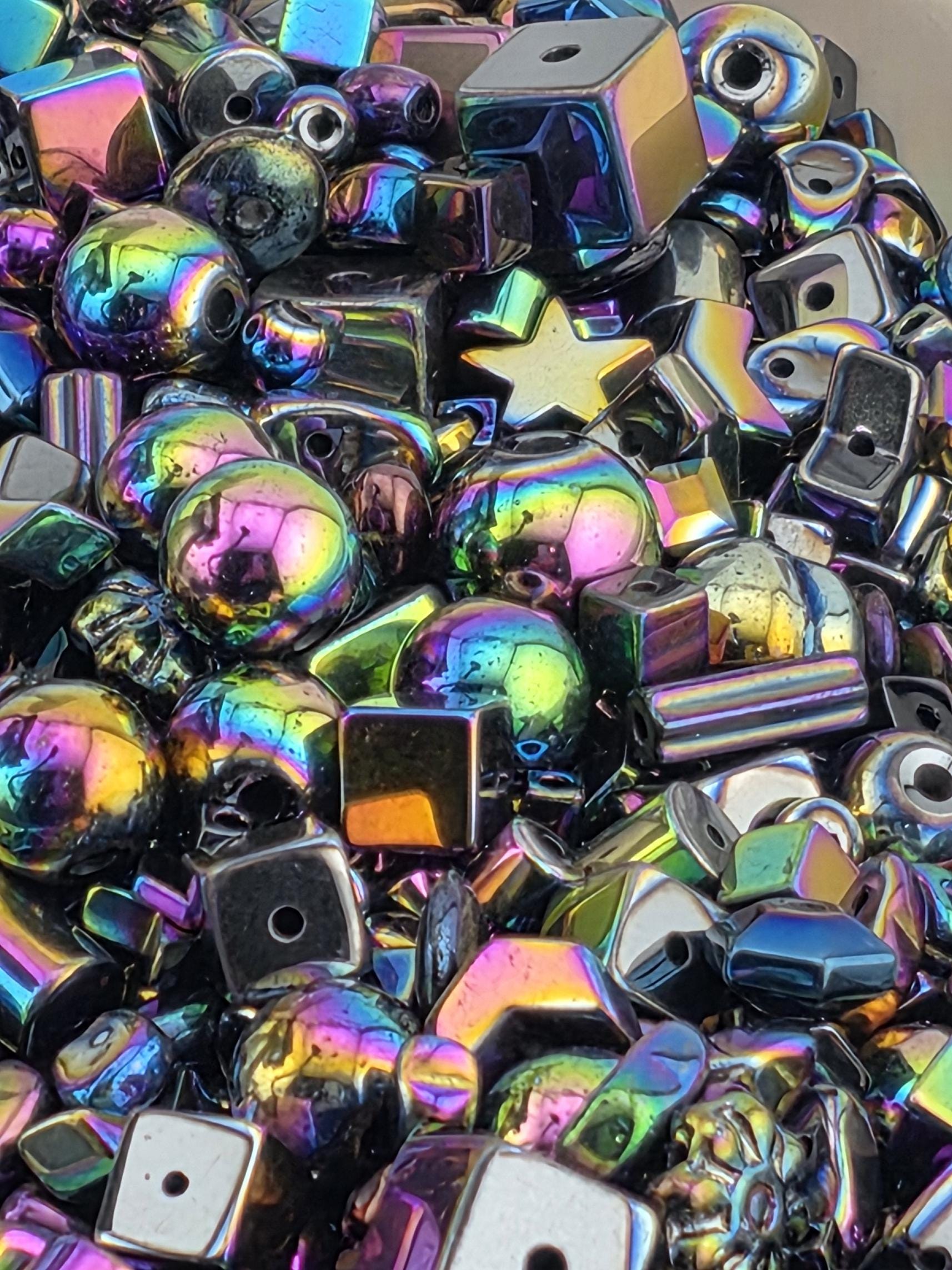 The image is a close-up of a pile of multicolored glass beads, including various shapes and sizes, creating a vibrant and visually striking display.