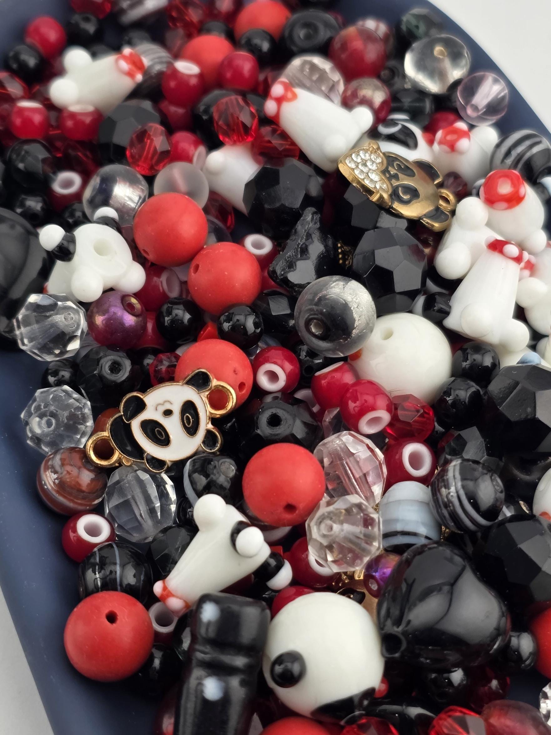 A colorful assortment of beads, charms, and other decorative items in various shapes and sizes, including clear beads, black and white beads, and red and white beads.