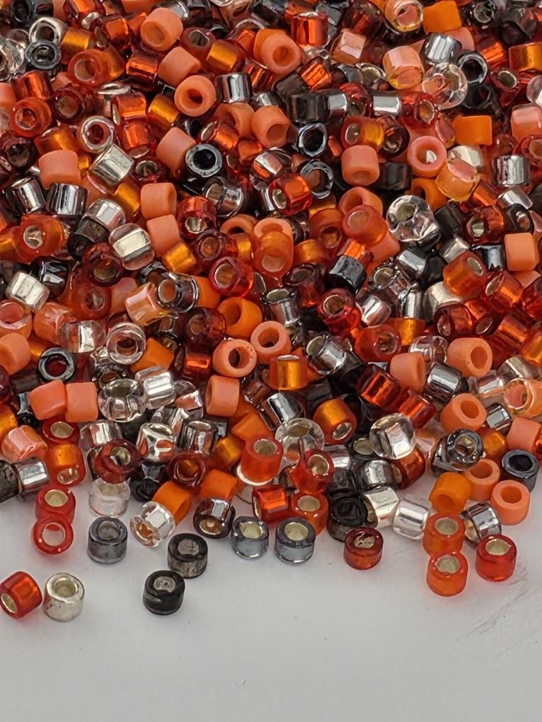 The image is a collection of various colored beads, including orange, black, and silver, scattered across a surface.
