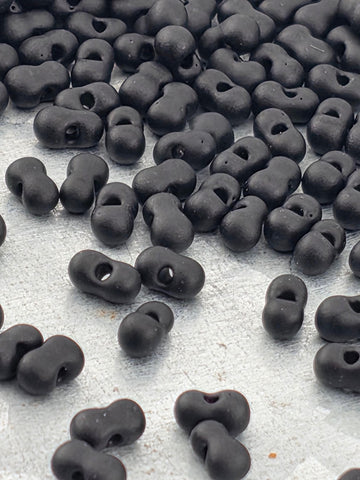 a collection of black beads or objects scattered on a white surface.