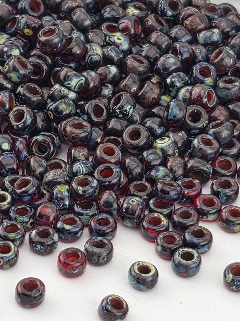 a large pile of multicolored glass beads scattered on a white surface.