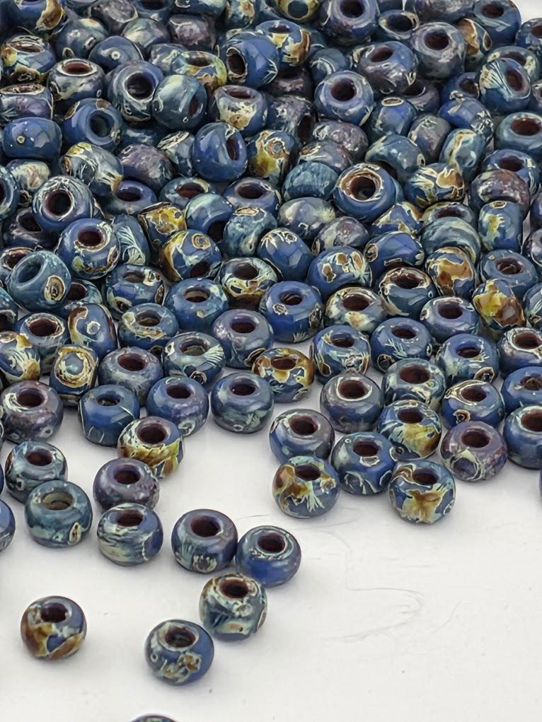 a large pile of blue and brown ceramic beads scattered on a white surface.