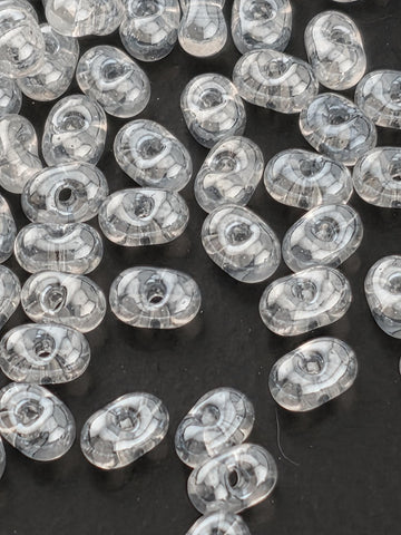 a collection of clear, oval-shaped glass beads scattered on a dark background.