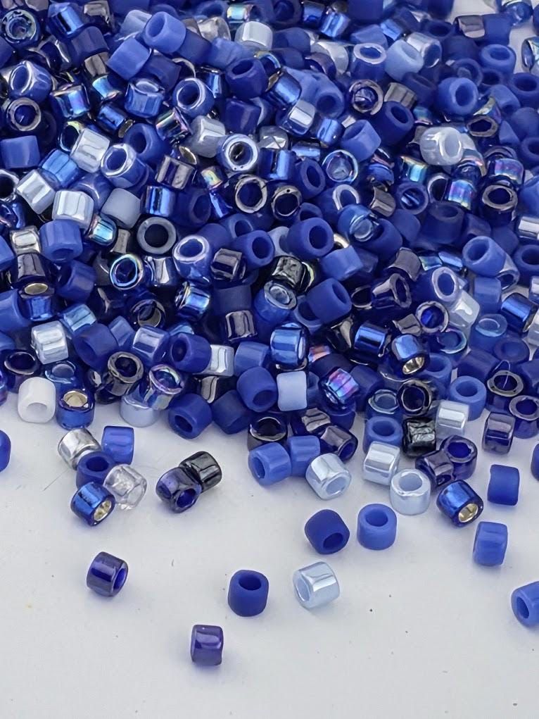 A pile of blue and silver beads scattered on a white surface.