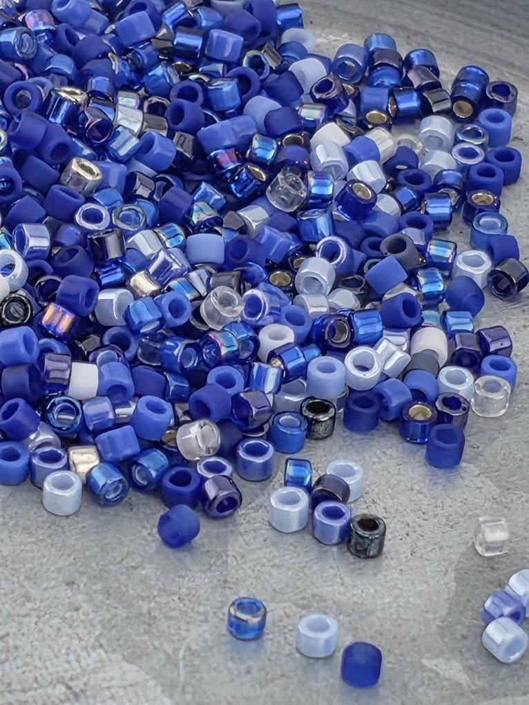 a large pile of blue and white beads scattered on a surface.