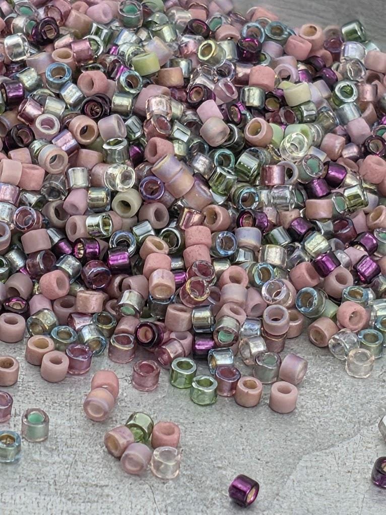 A pile of multicolored glass beads in various shades of pink, purple, and green.
