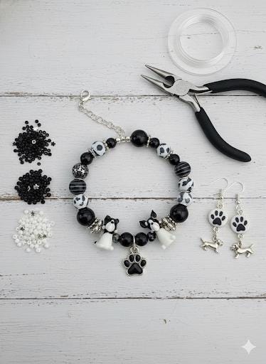 A collection of various beads, charms, and other decorative items in shades of black and white, including small animal figurines and other playful elements.