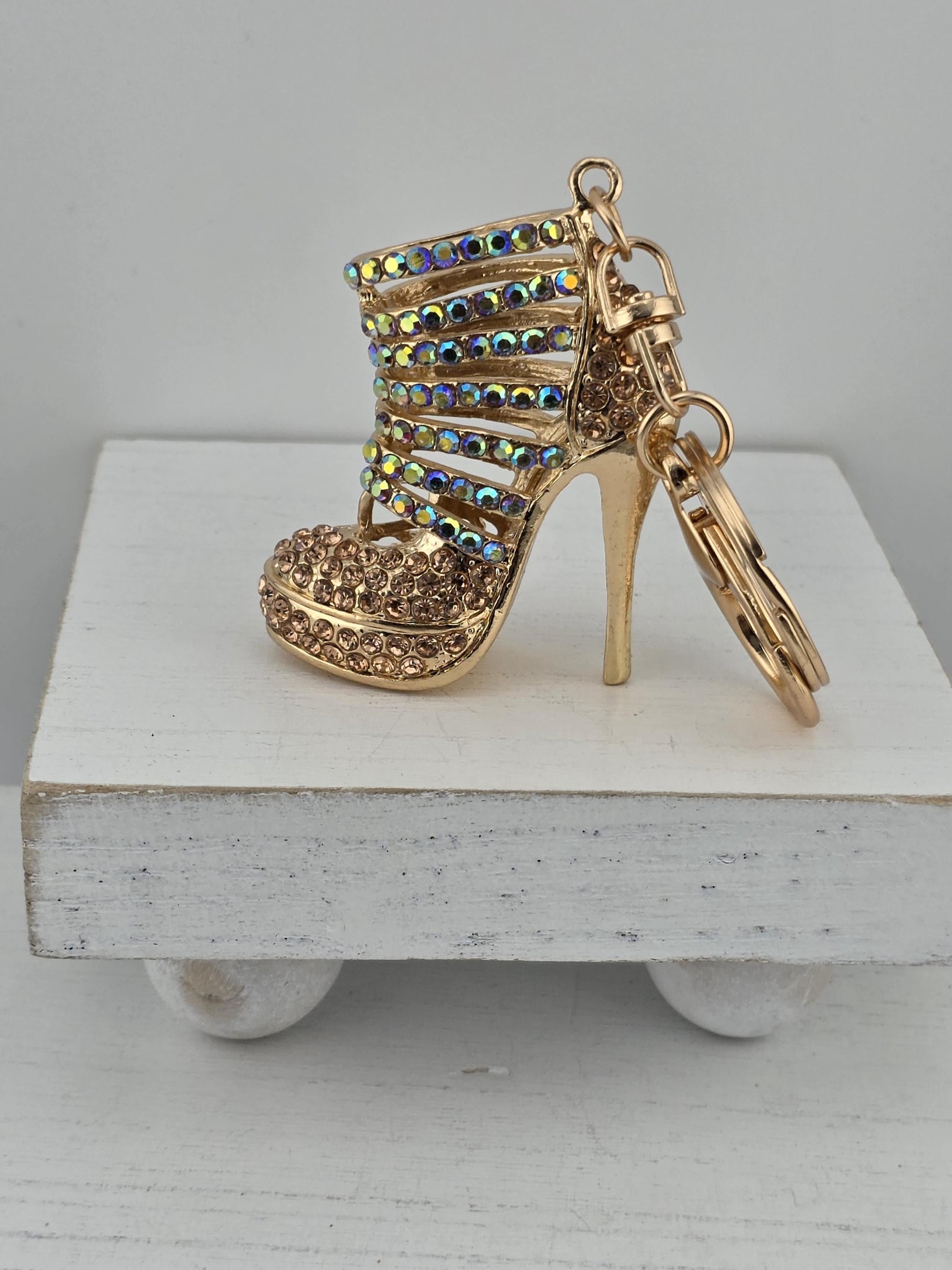 A gold-colored high-heeled shoe keychain with rhinestones and a dangling design.